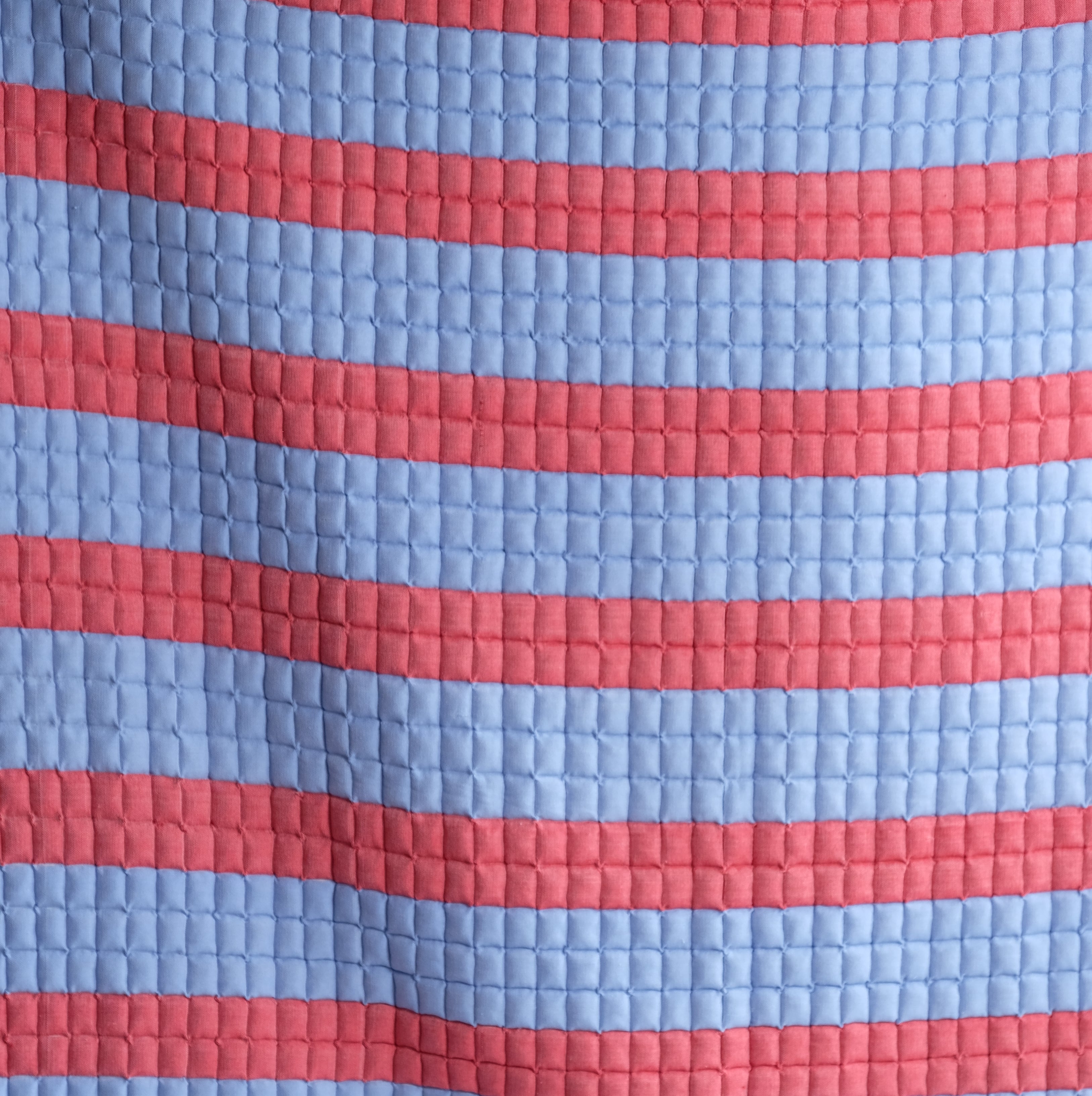 Close-up of red and blue striped sujani quilt with quilted pattern