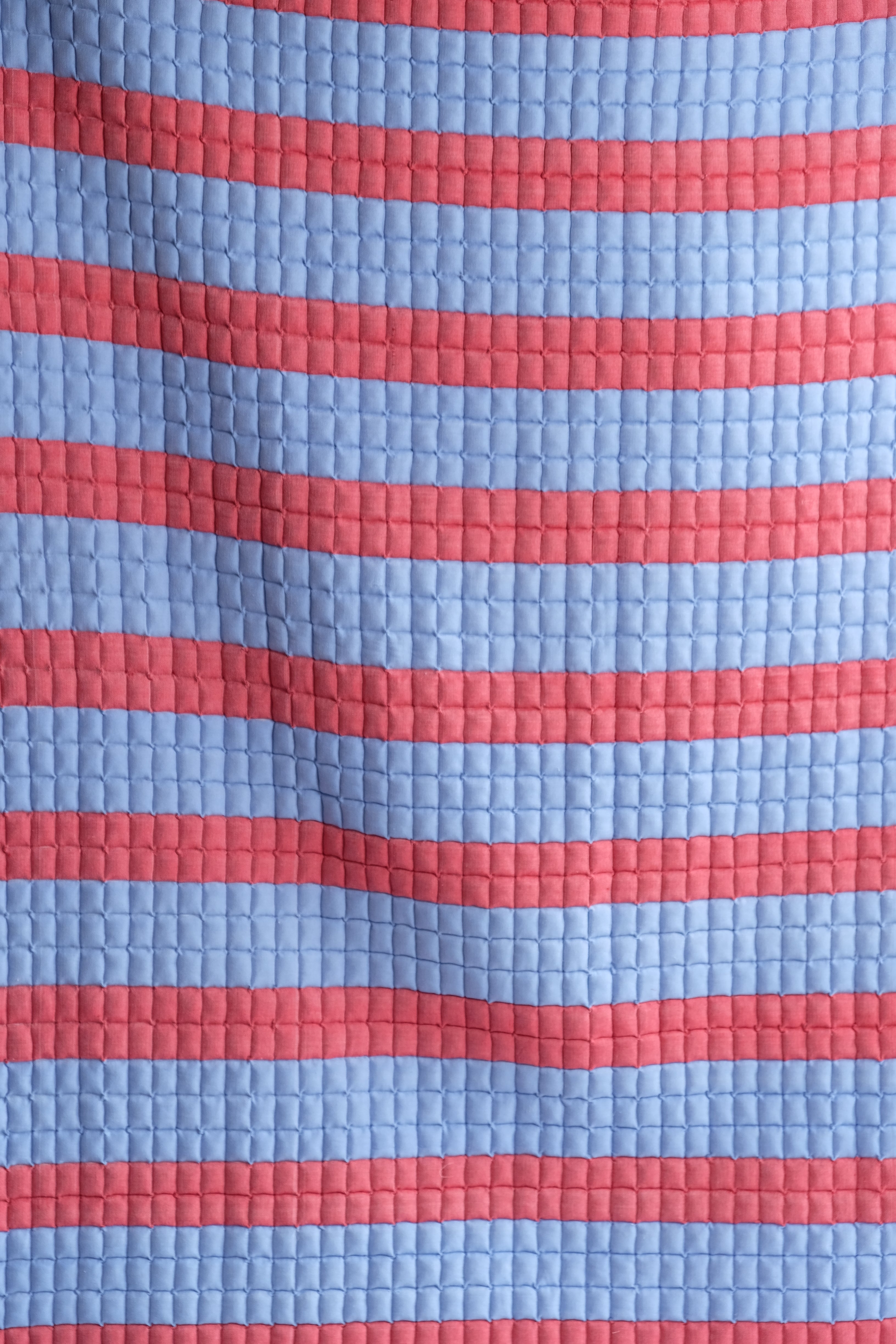 Close-up of red and blue striped sujani quilt with quilted pattern