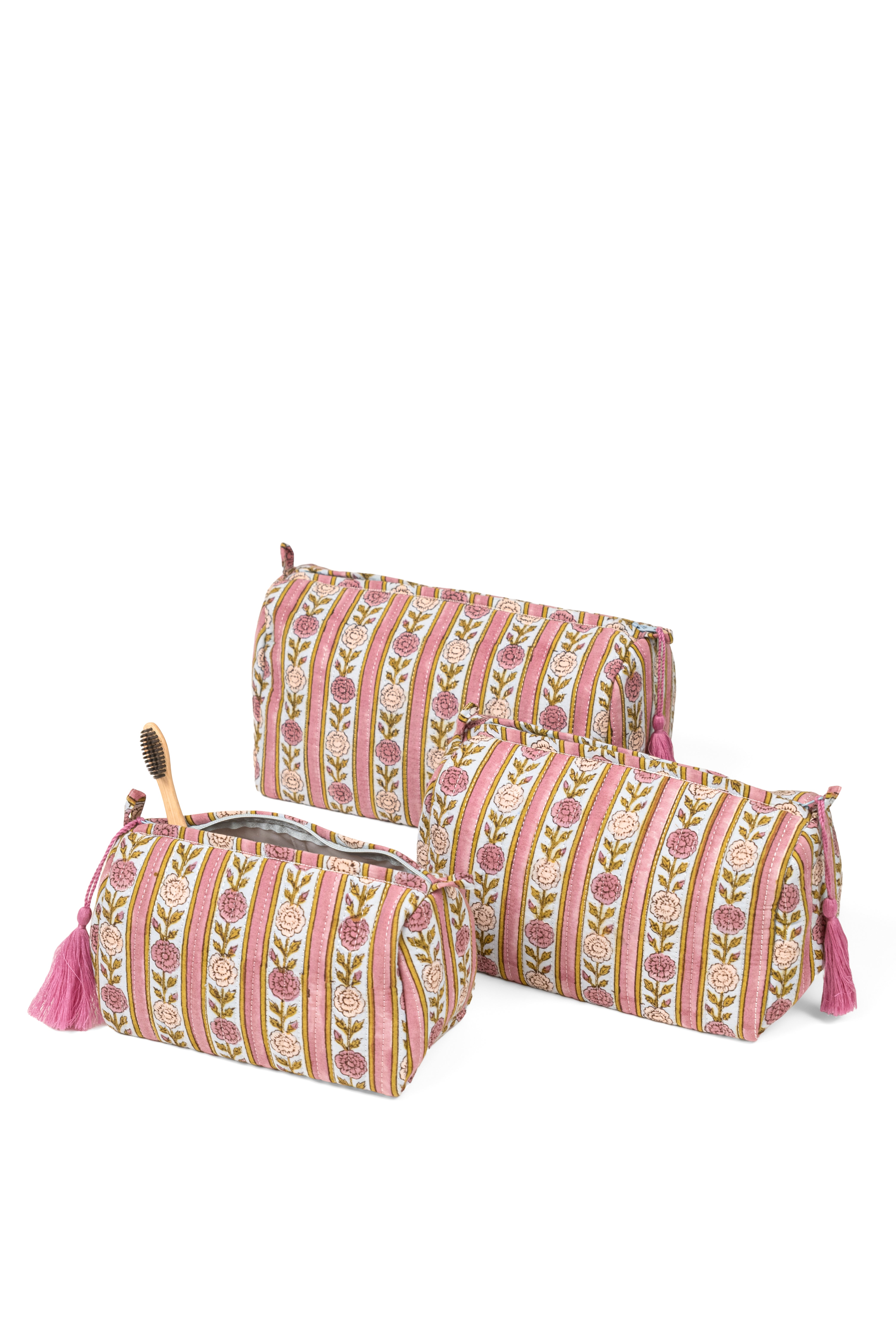 Three vintage floral striped makeup bags with one open revealing wooden brush