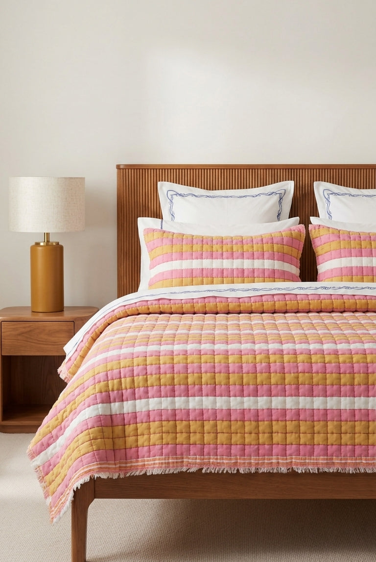 Bed with pink and yellow striped bedding in a bedroom setting.