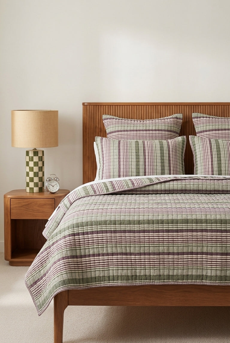 Bedroom with wooden bed, plaid bedding, and nightstand with lamp.