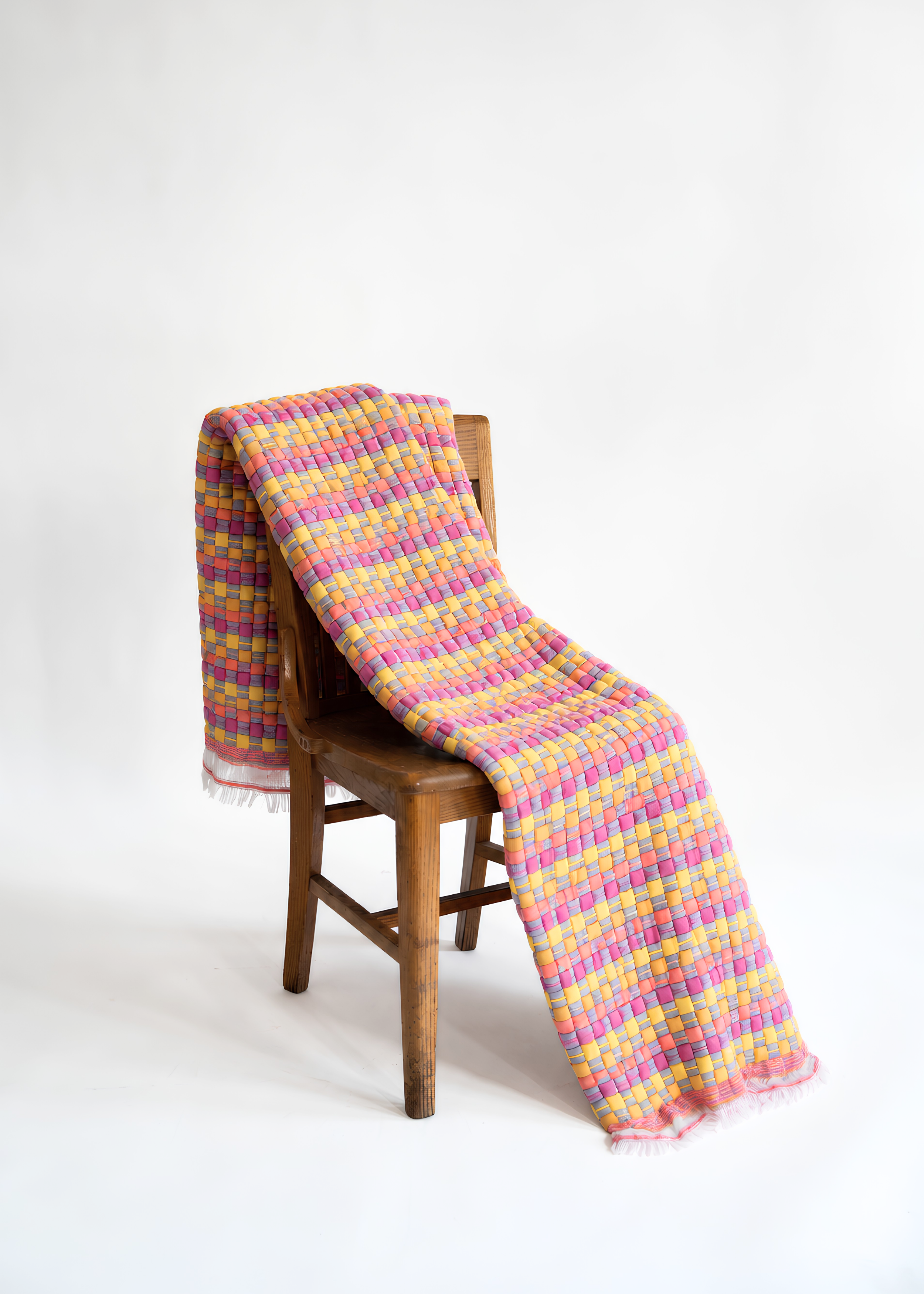 Vibrant cotton candy colored sujani quilt draped over wooden chair