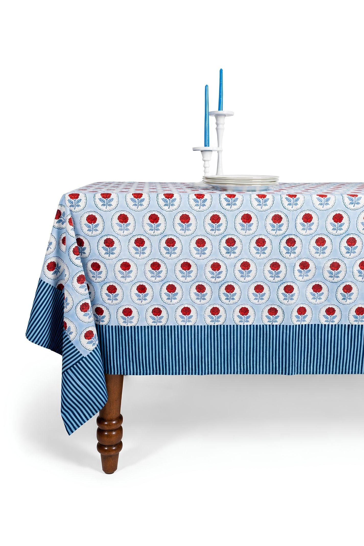 Inner Child red rose blockprint tablecloth draped over wooden table with blue striped border