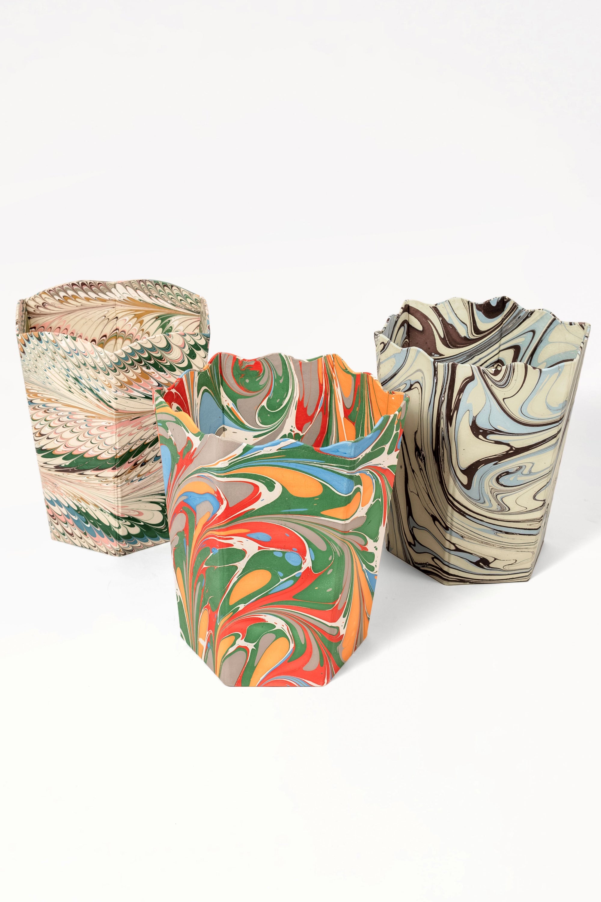 Group of hand-marbled scallop waste bins with diverse marbling patterns