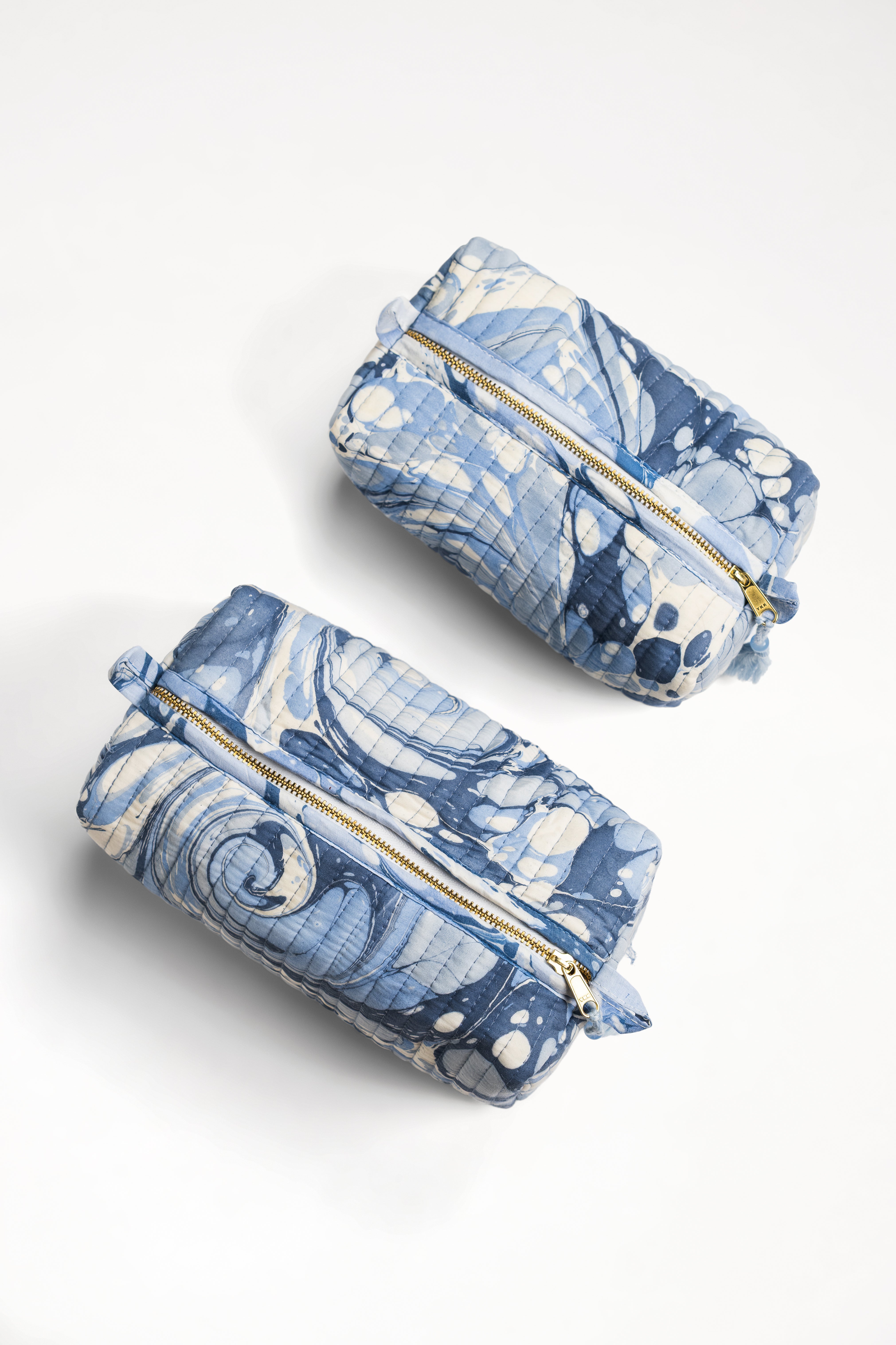 Two hand-marbled ocean wave cosmetic bags displayed from angled position
