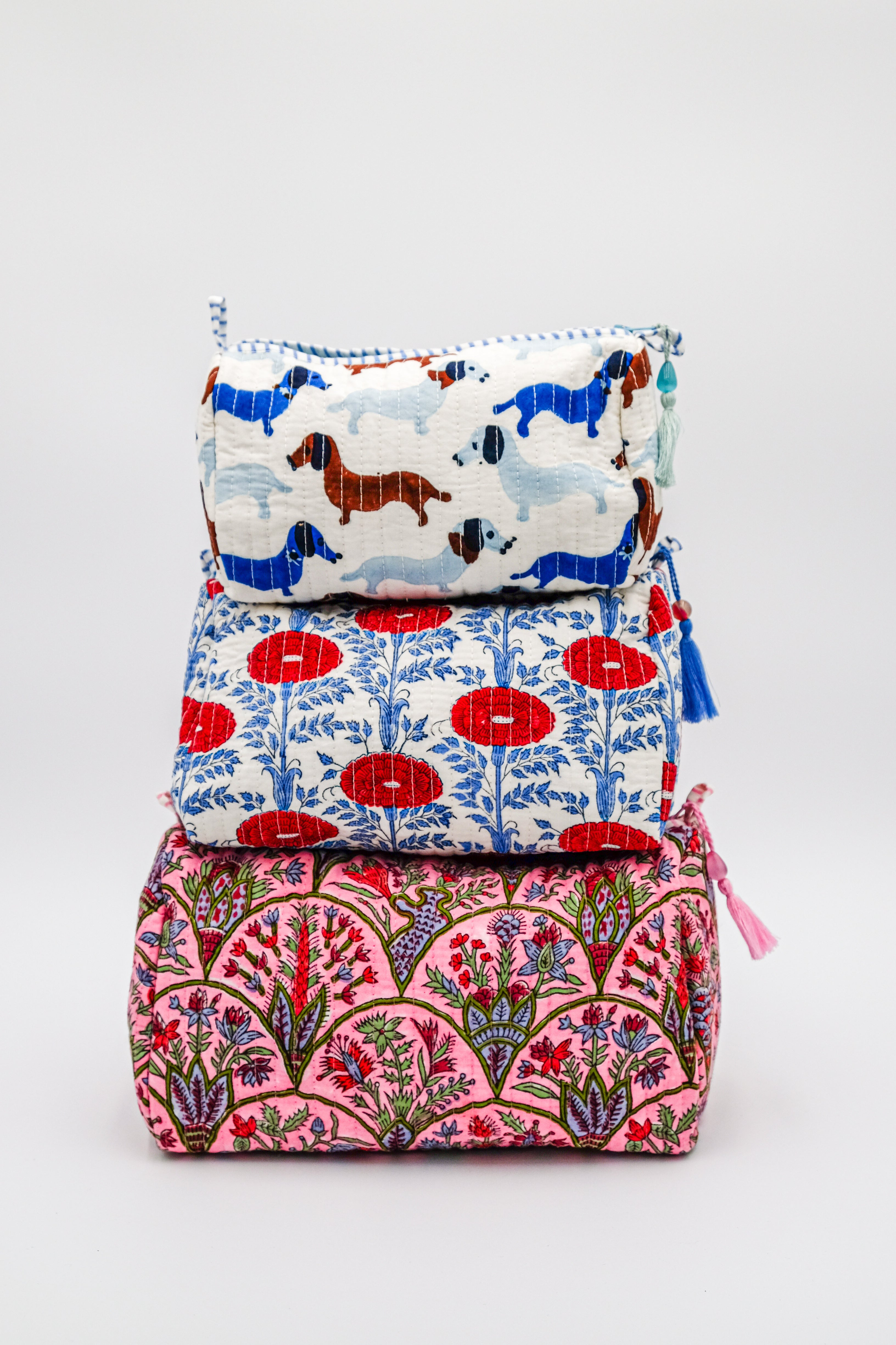 Stacked toiletry bags with colorful patterns including dog prints and floral designs from Inner Child