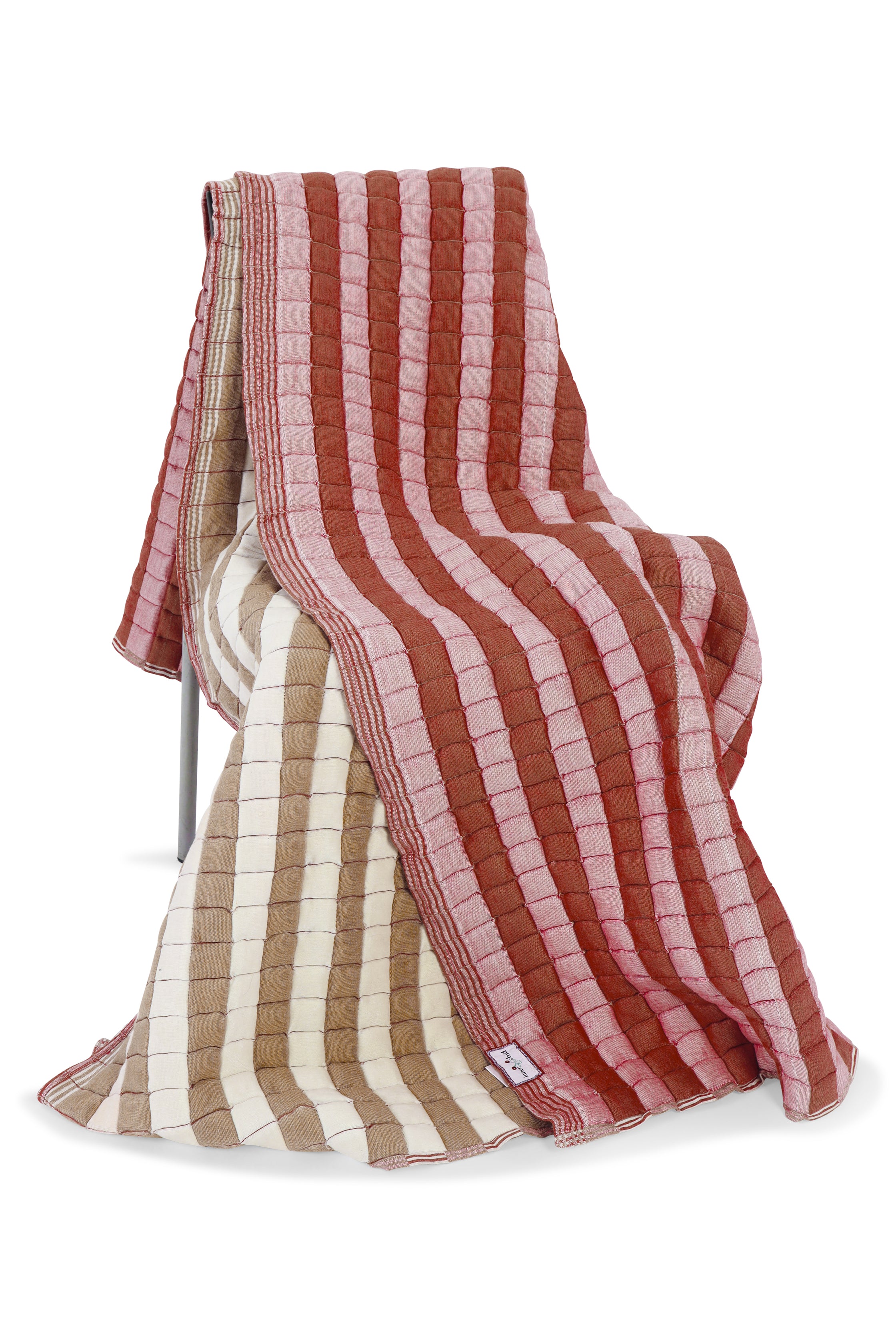 Warm taupe and dusty pink reversible sujani quilt draped over chair, revealing beige reverse side