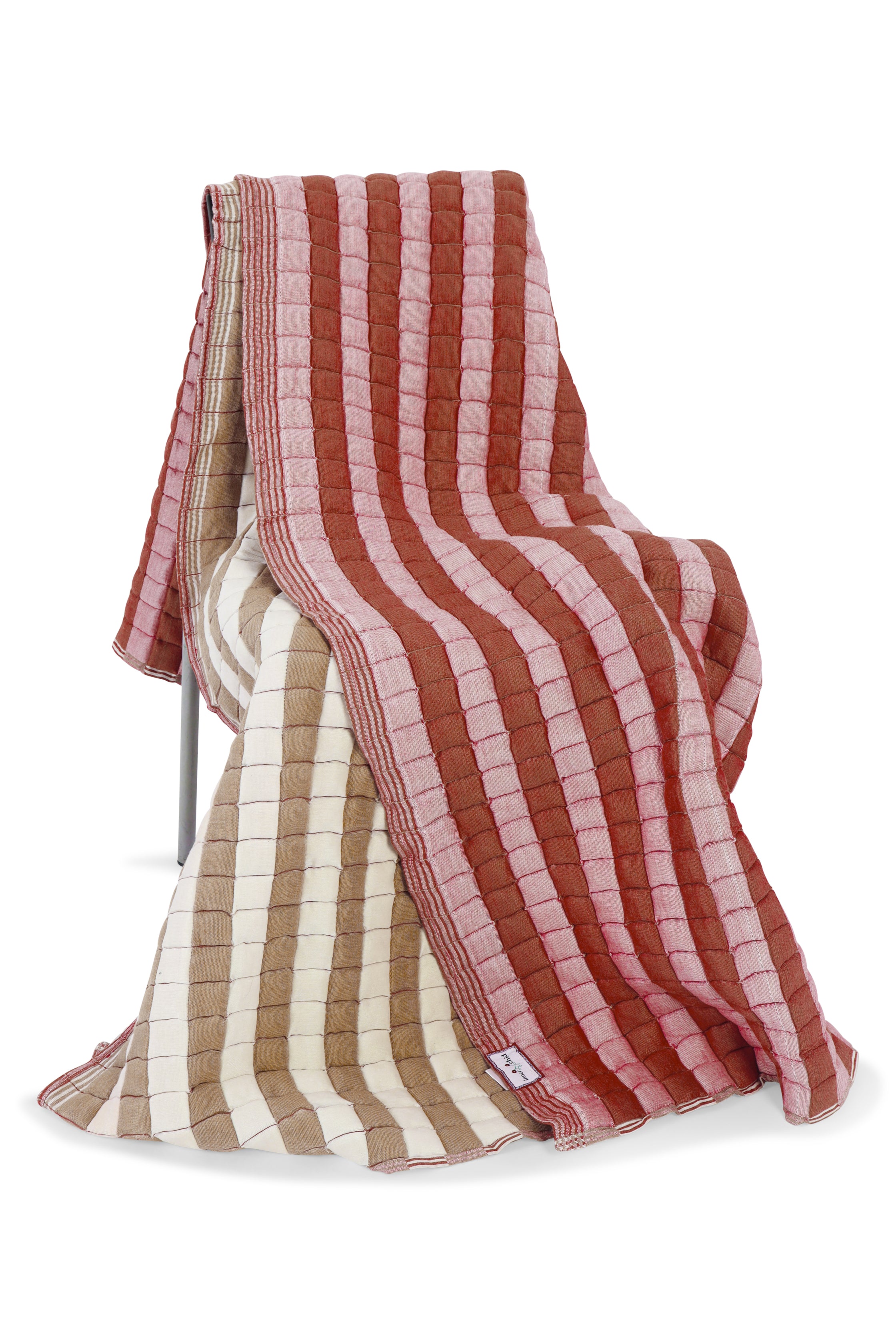 Warm taupe and dusty pink reversible sujani quilt draped over chair, revealing beige reverse side