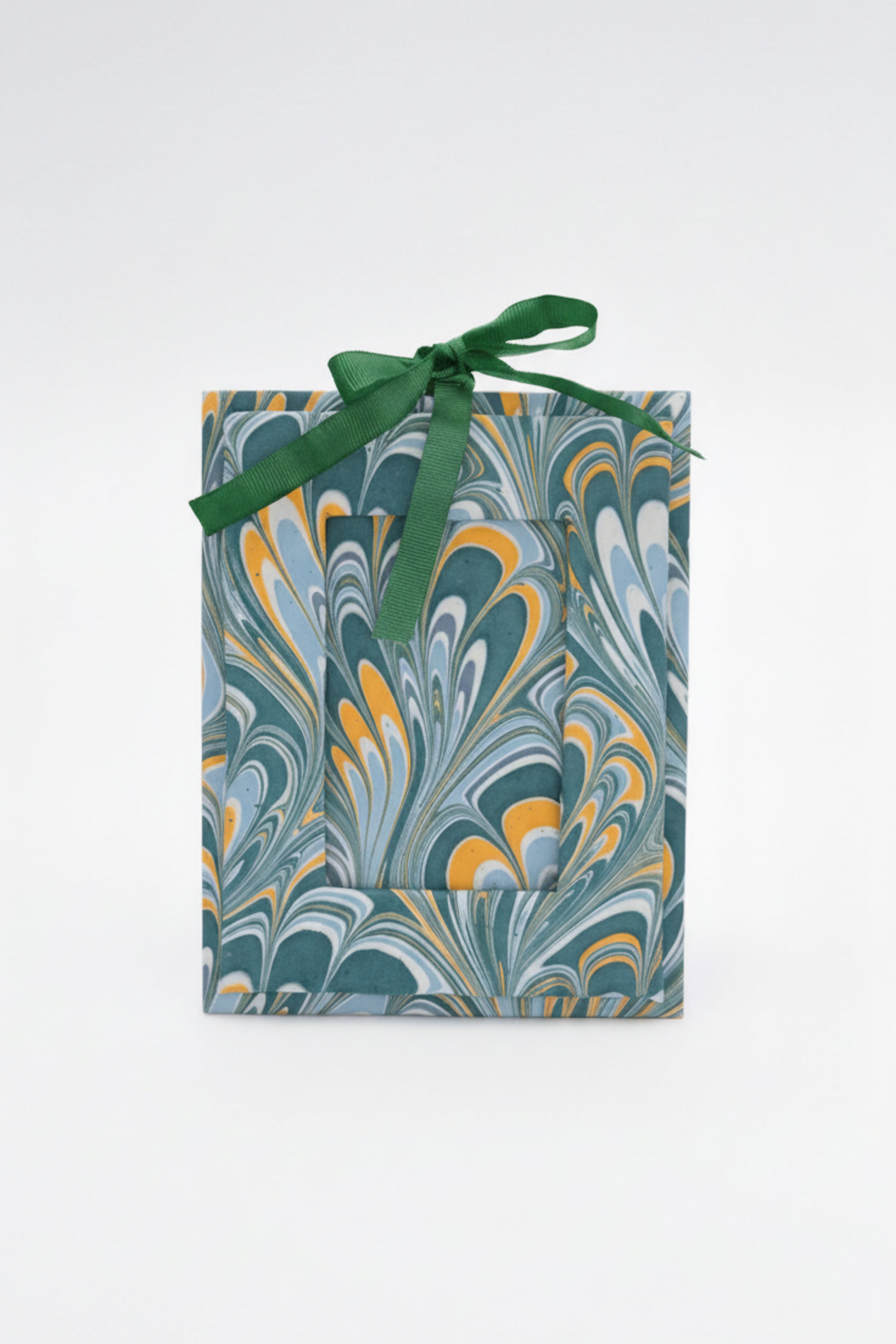 Green ribbon-tied hand-marbled mini picture frame ornament with blue/yellow swirls on white background