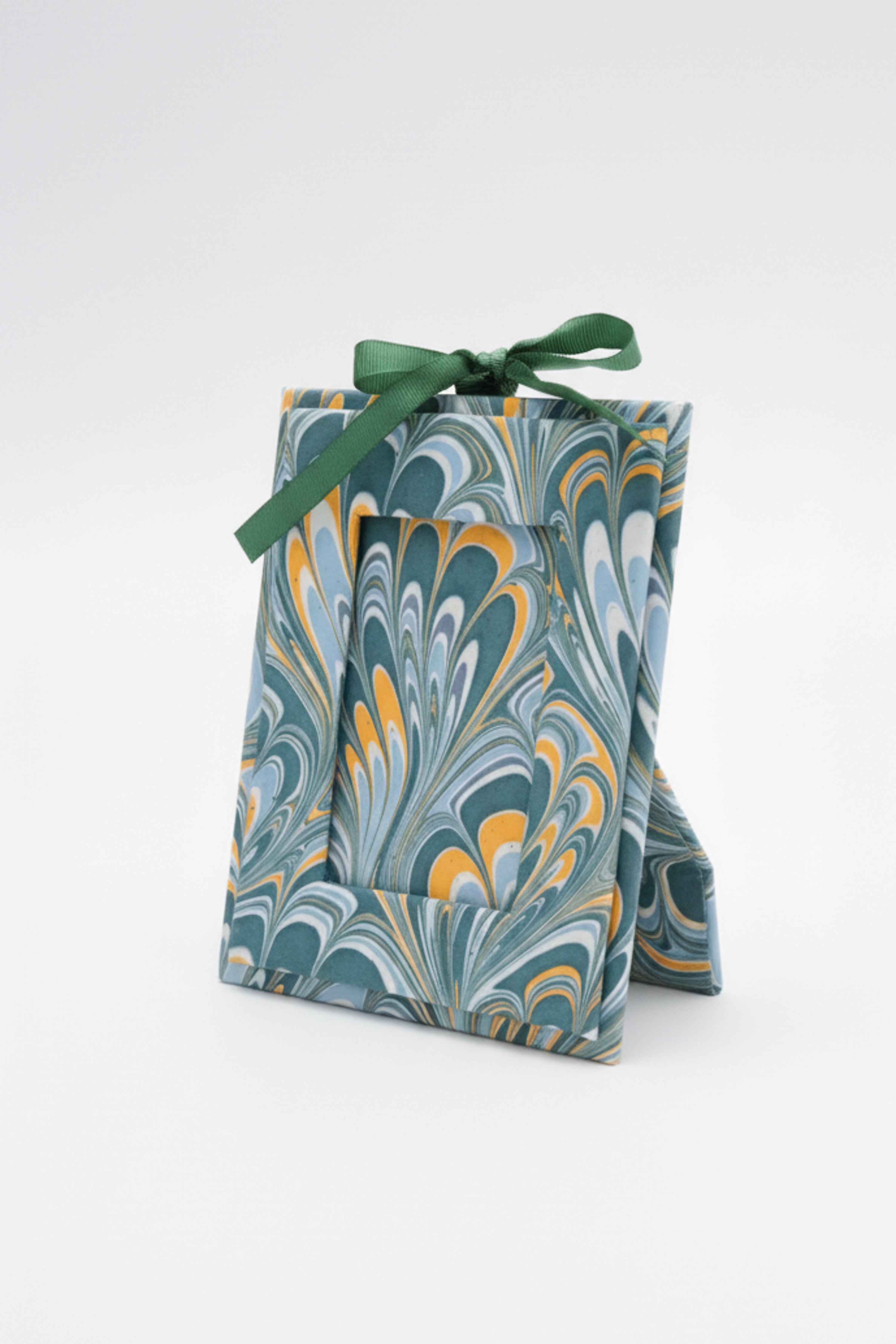 Green ribbon-tied hand-marbled mini picture frame ornament standing upright on white surface