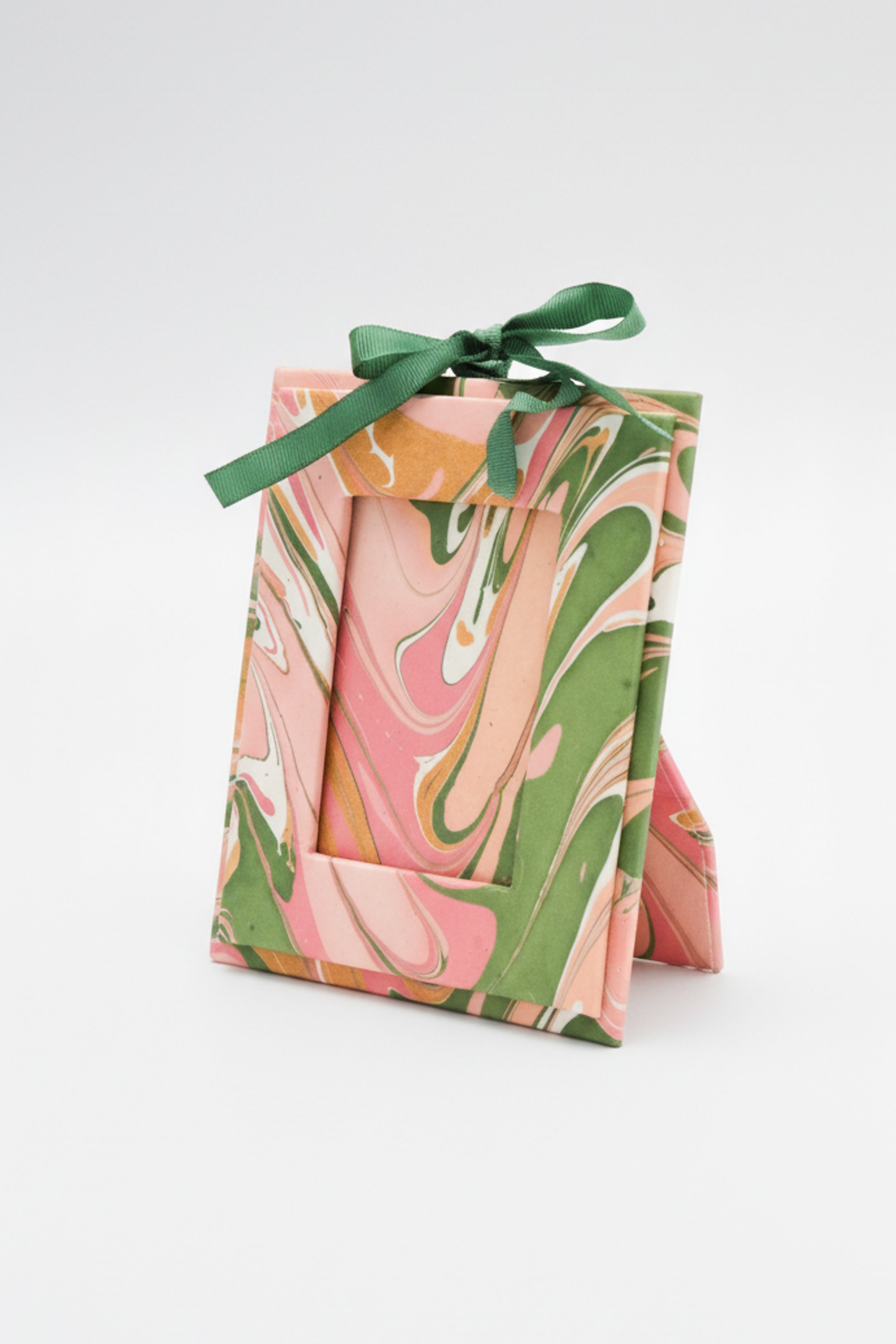 Mini hand-marbled peony bloom picture frame ornament standing upright with green ribbon