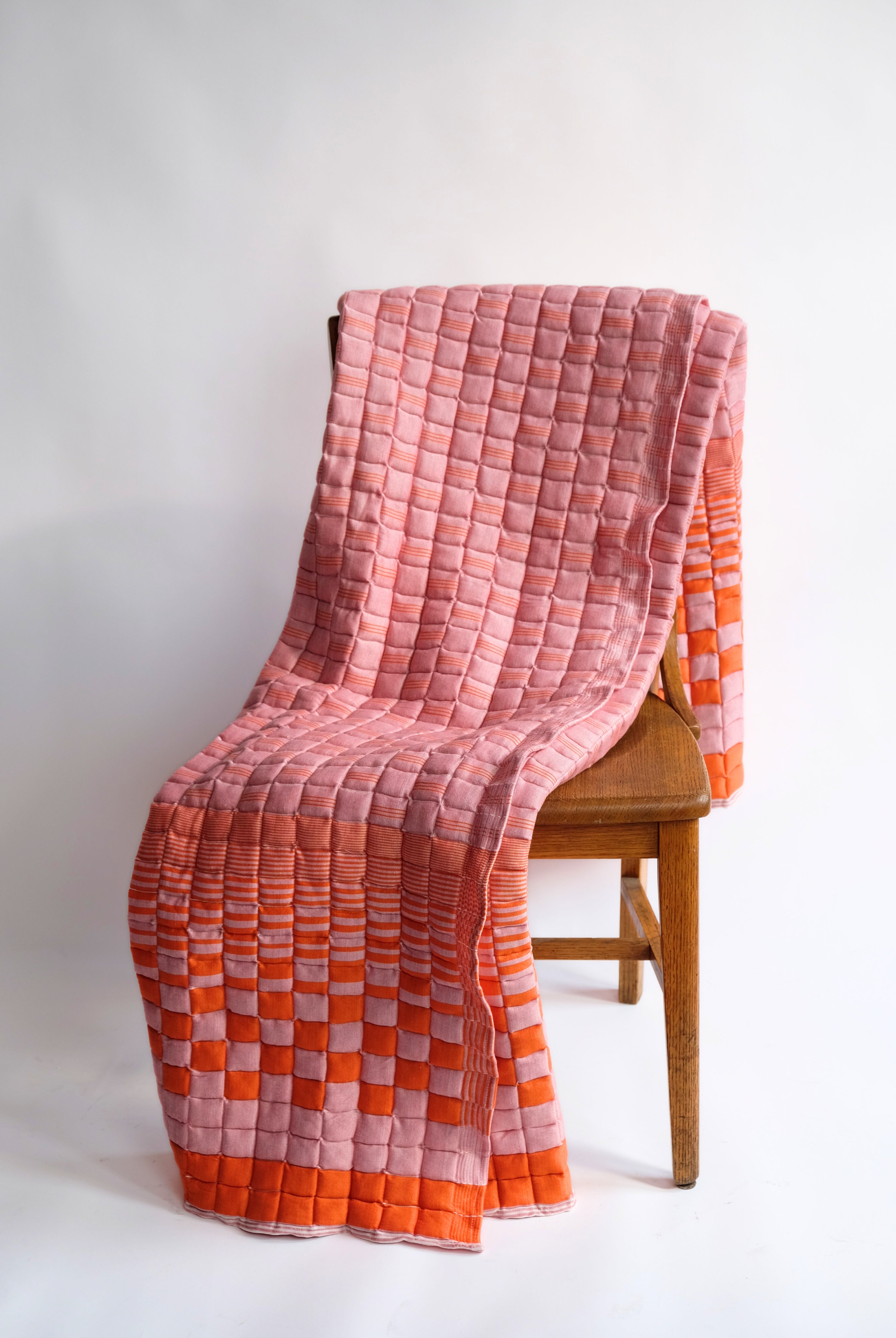 Bold orange and pink reversible sujani quilt draped over wooden chair - Inner Child