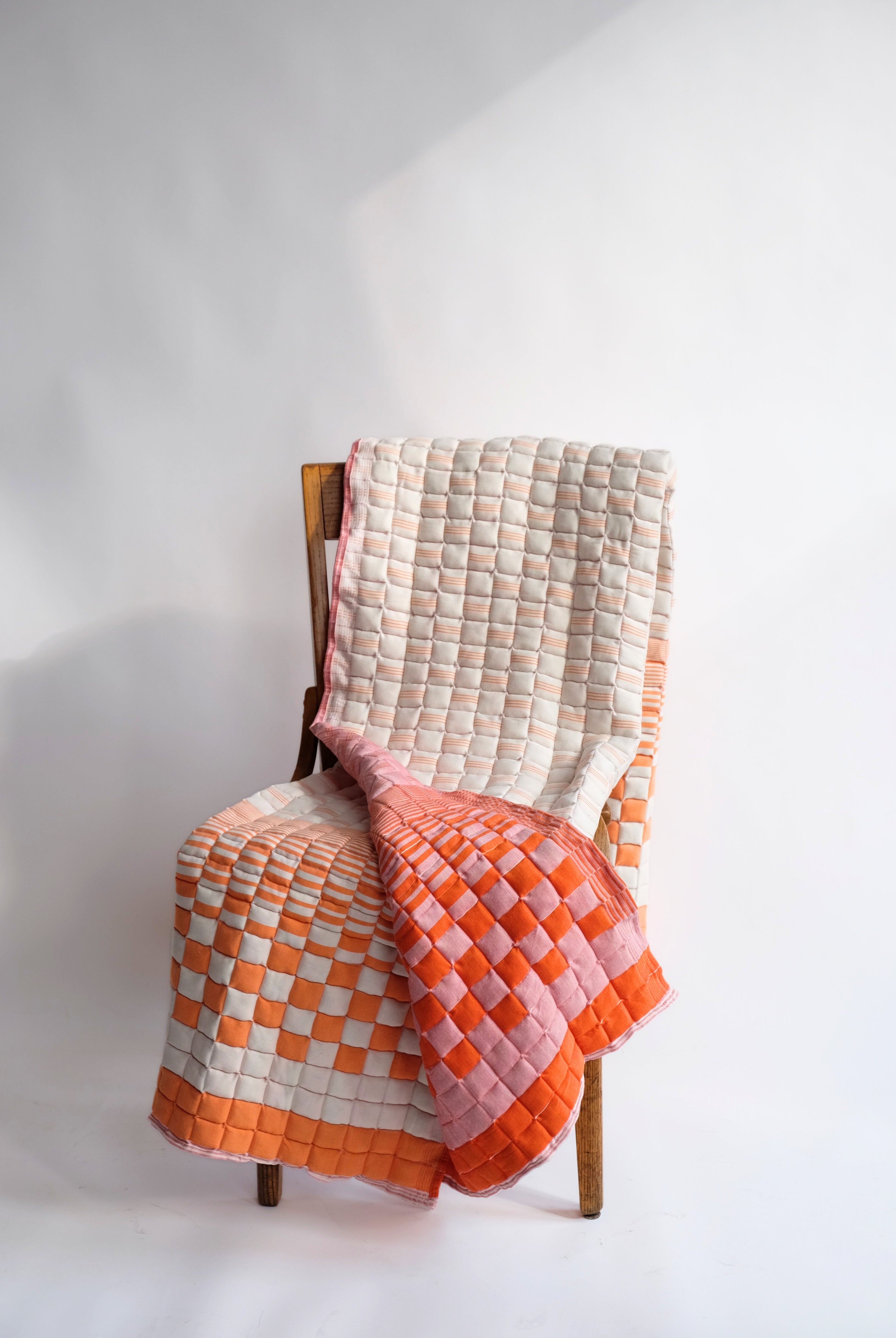Bold orange and pink reversible sujani quilt draped over wooden chair - Inner Child