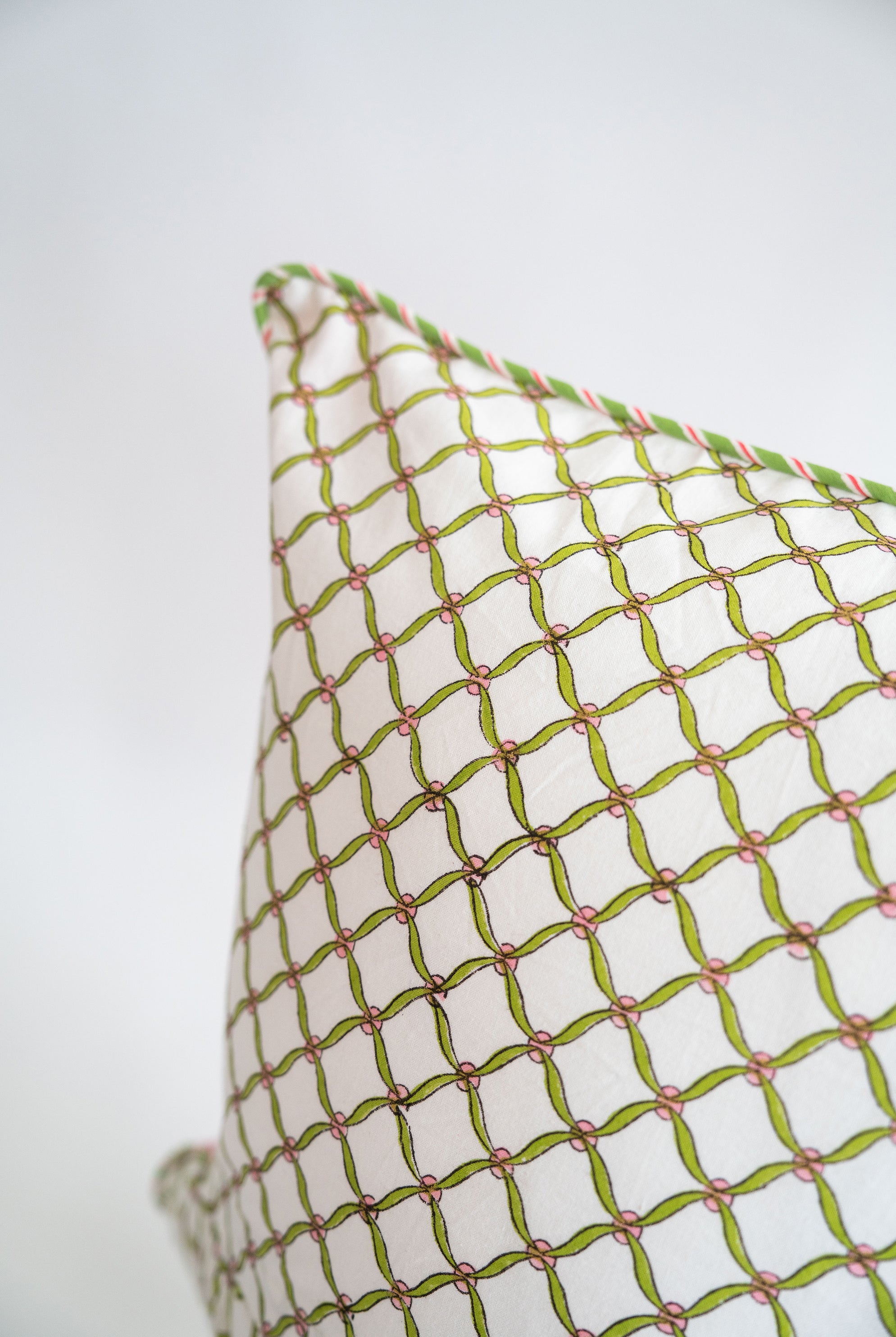 White decorative pillow with green and pink blockprint geometric pattern