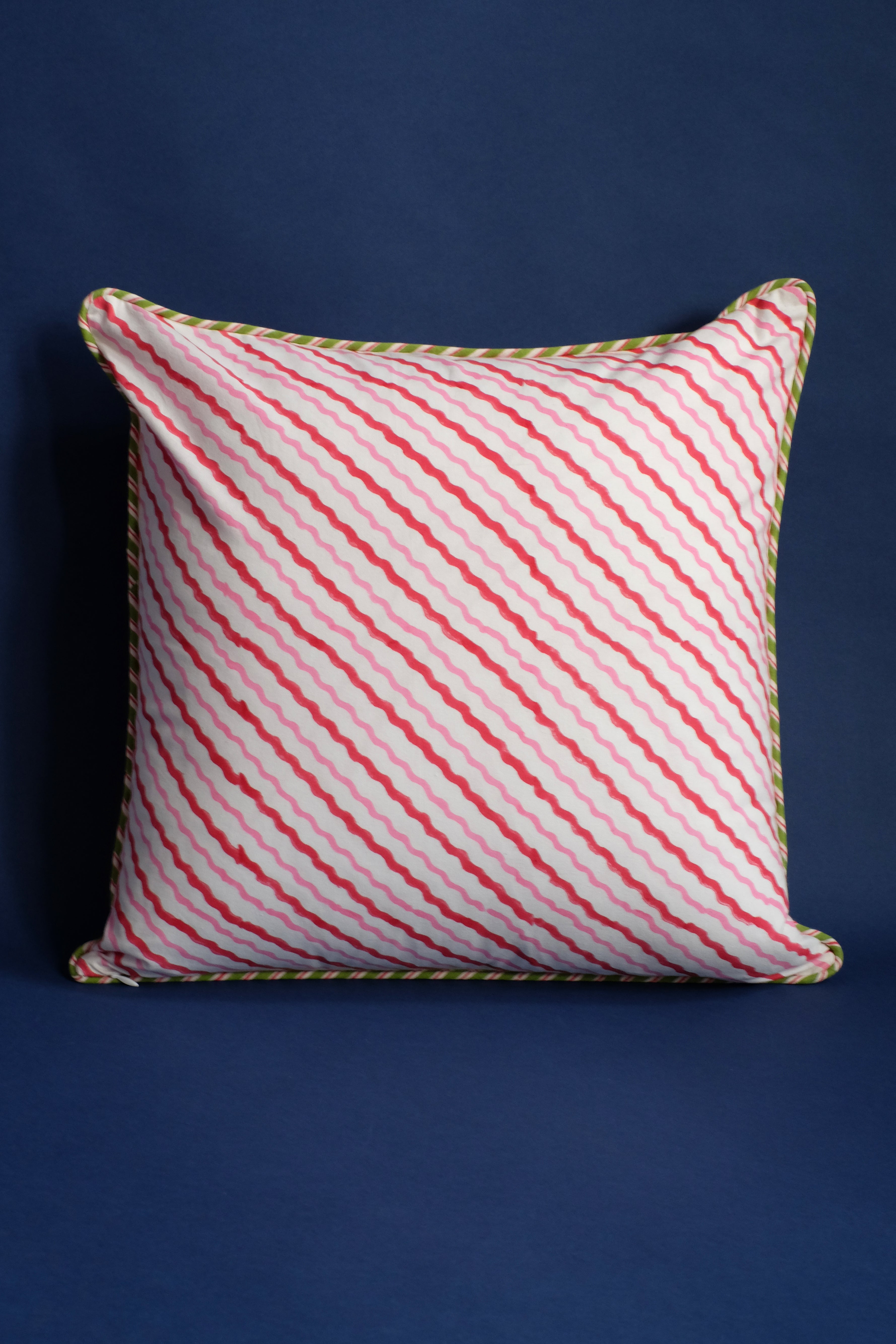 Decorative pillow with pink/red striped pattern and green trim detail
