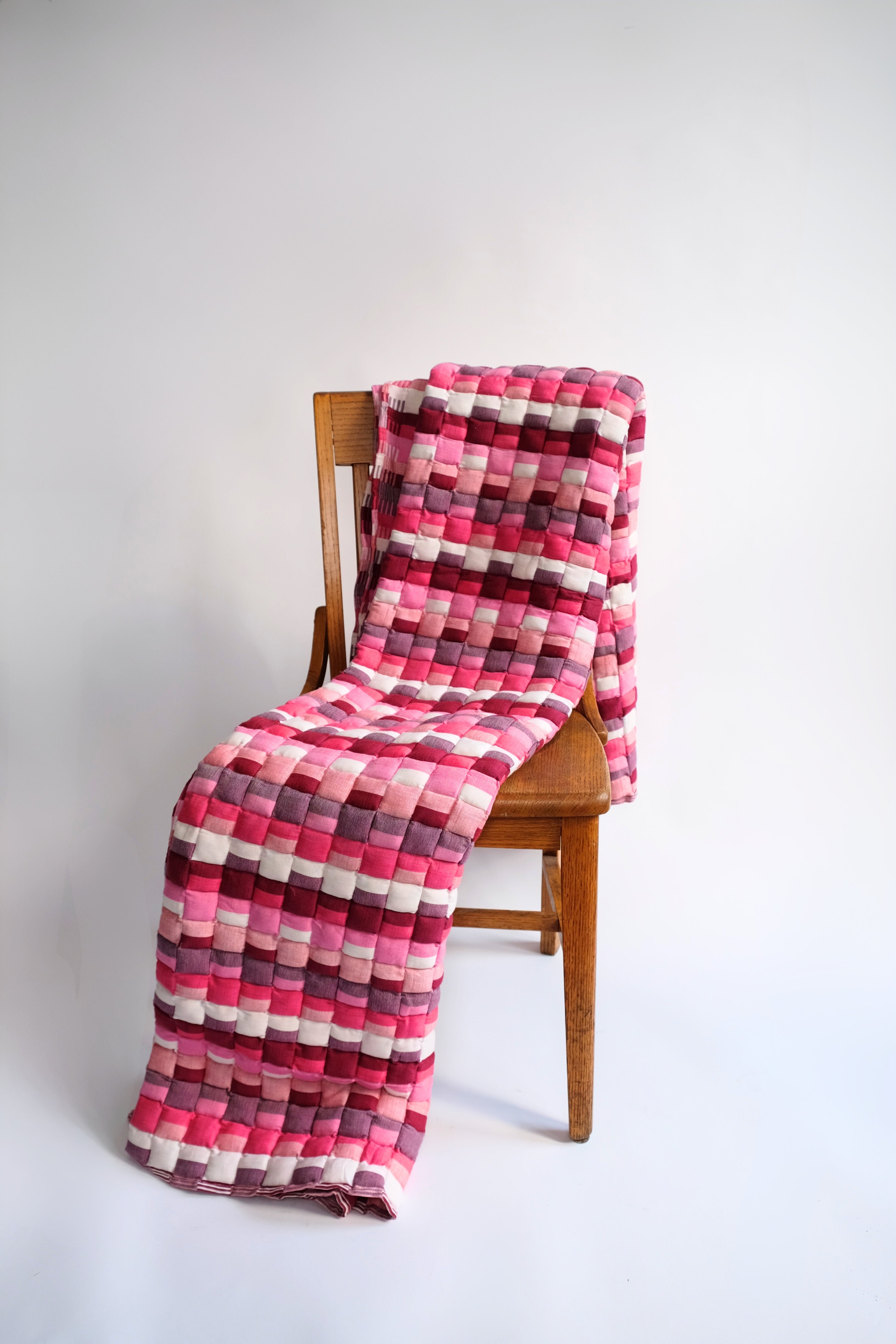 Pink Tetris Sujani quilt draped over wooden chair