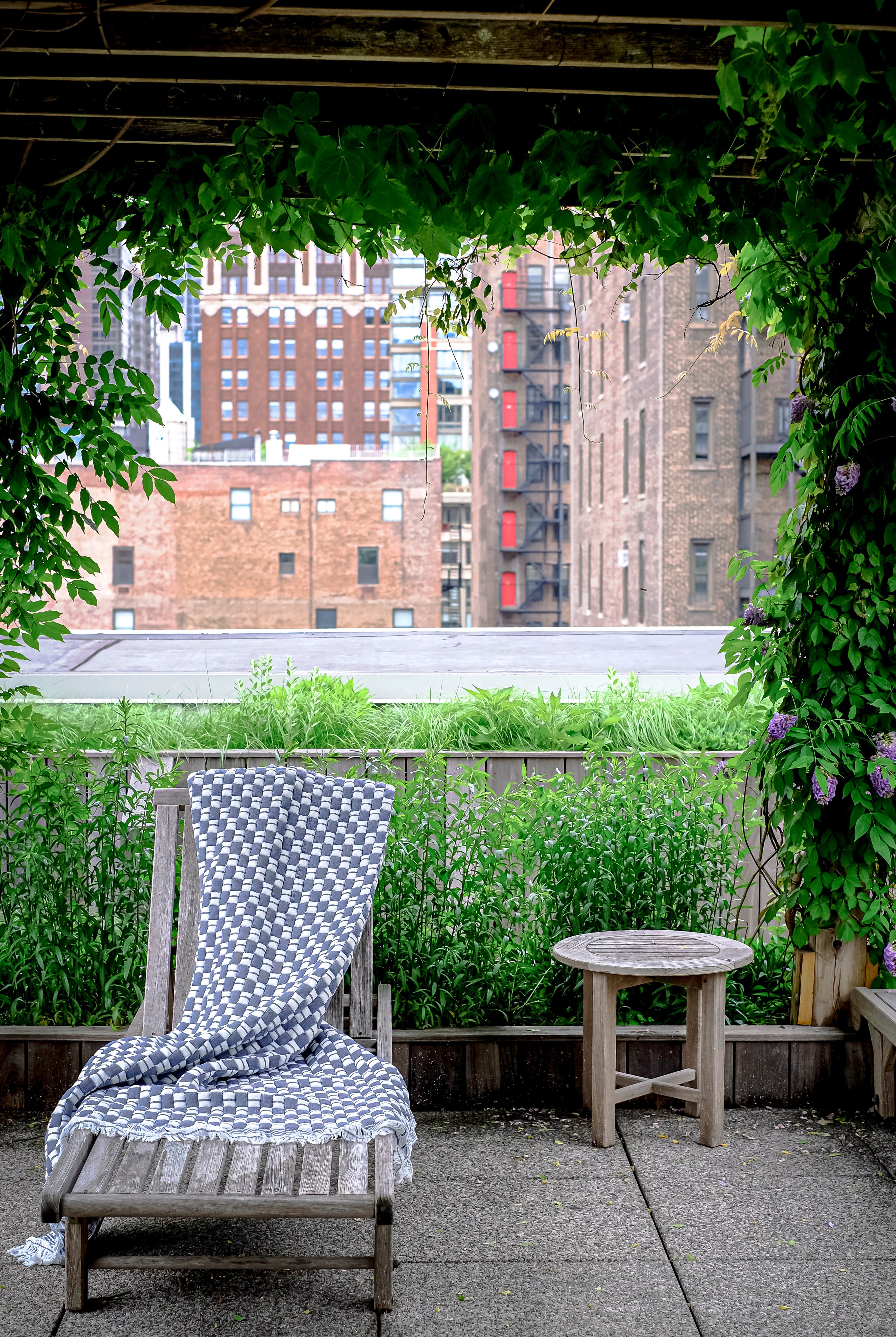 Blue checkered Sujani quilt on outdoor lounge chair with city view