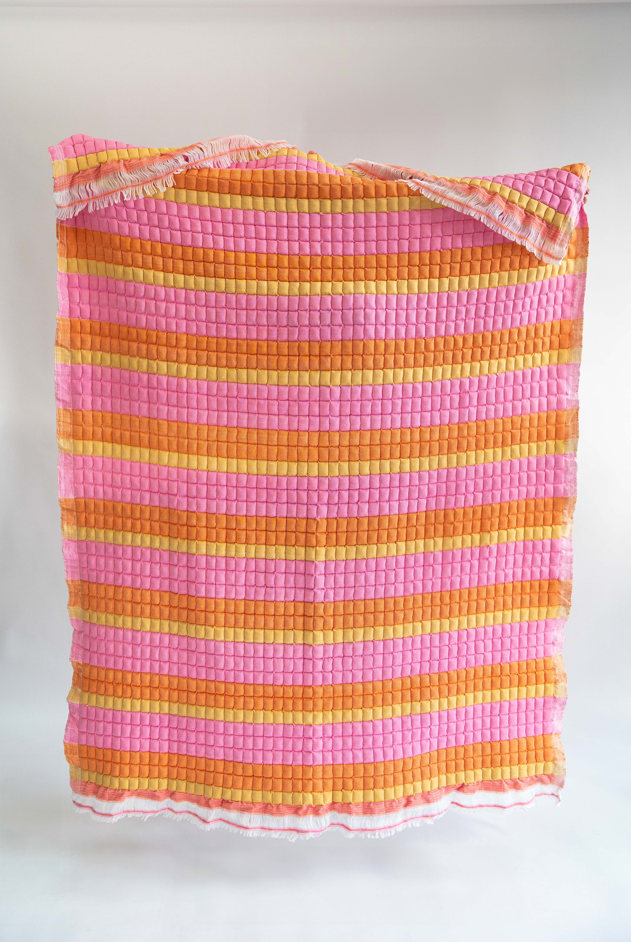 Inner Child Creamsicle Sujani quilt with pink/orange/yellow stripes and fringe edges