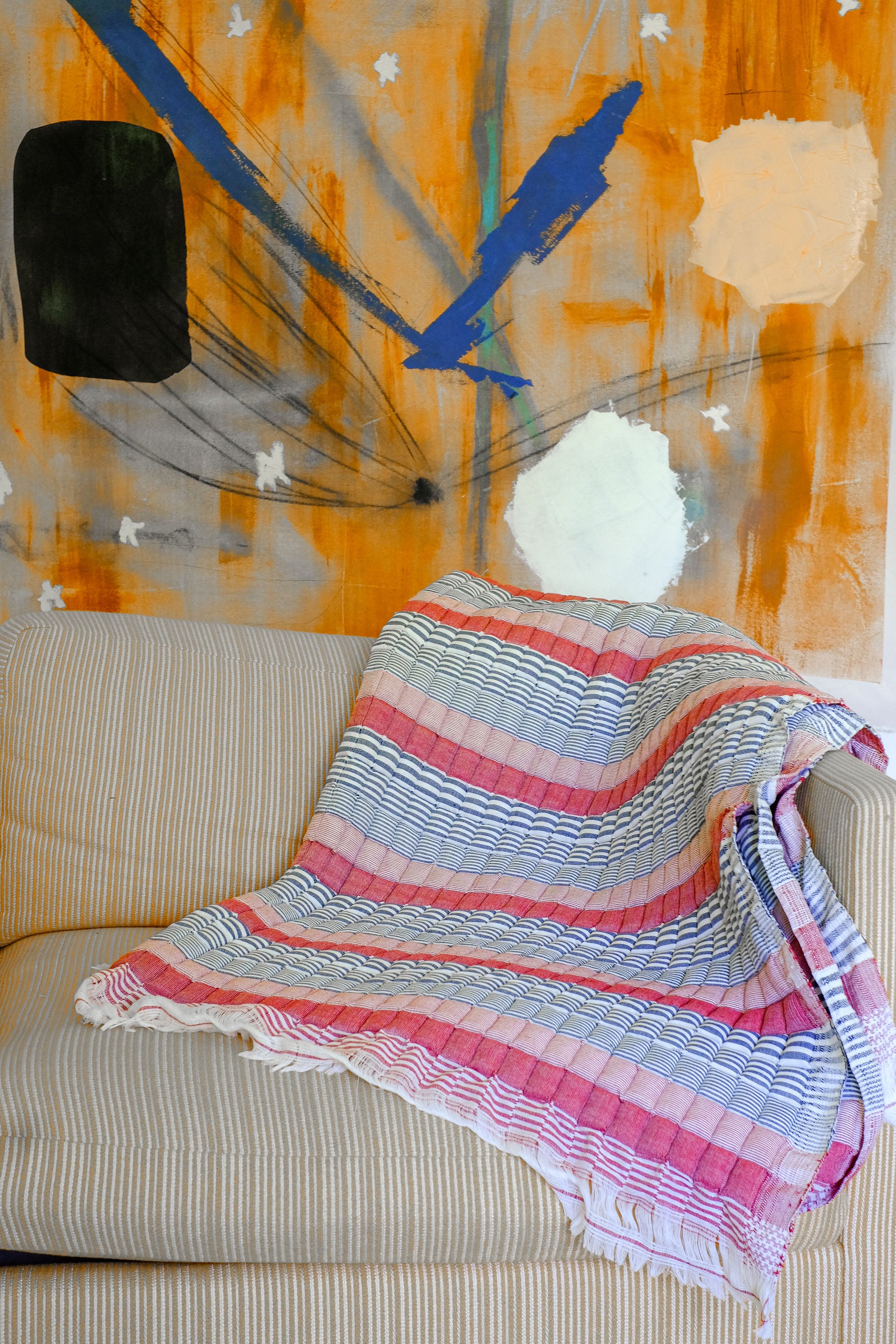 Inner Child Americana Sujani quilt with red/pink/blue stripes on beige couch