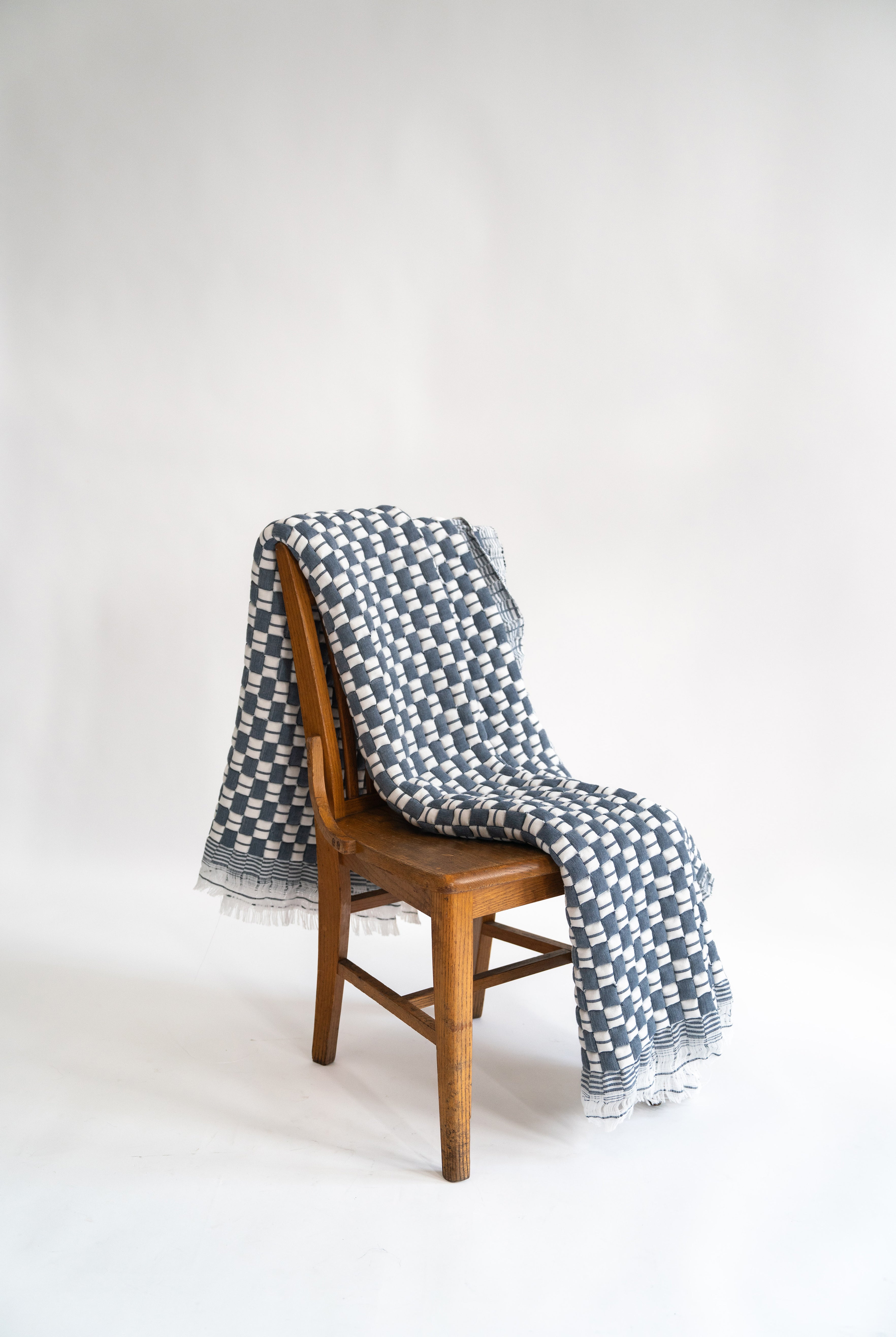 Blue checkered Sujani quilt draped over wooden chair