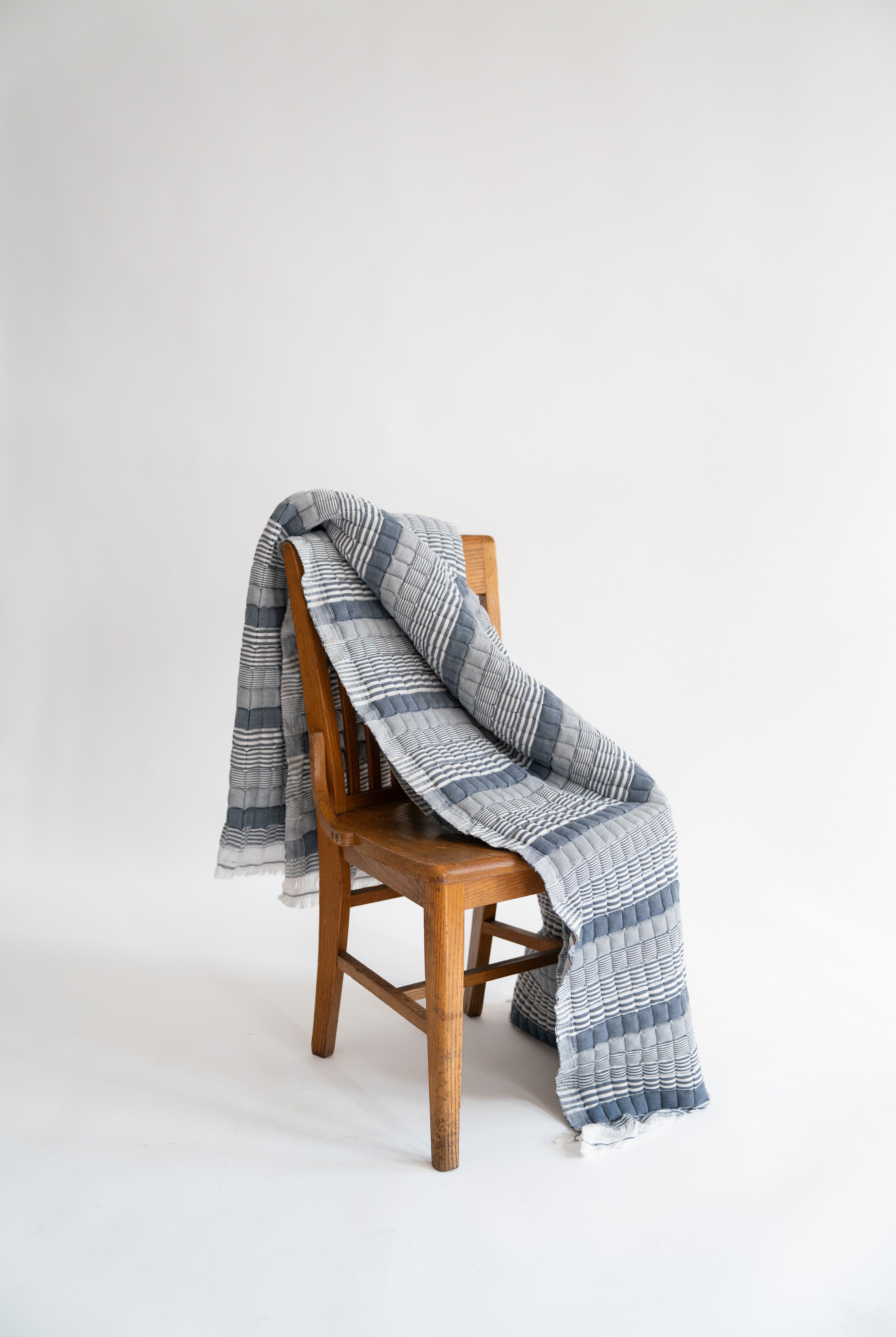 Blue striped Sujani quilt draped over wooden chair