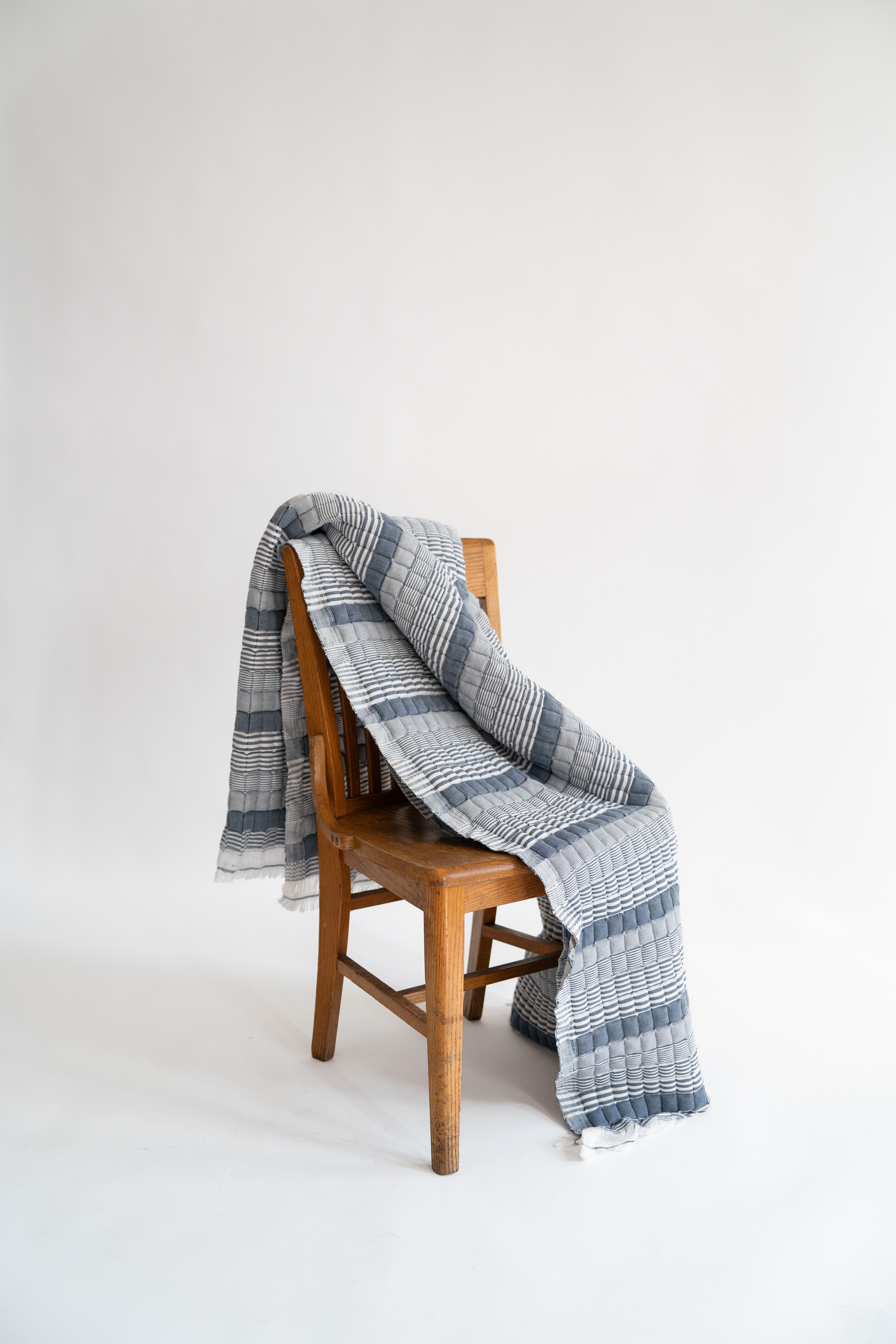 Blue striped Sujani quilt draped over wooden chair