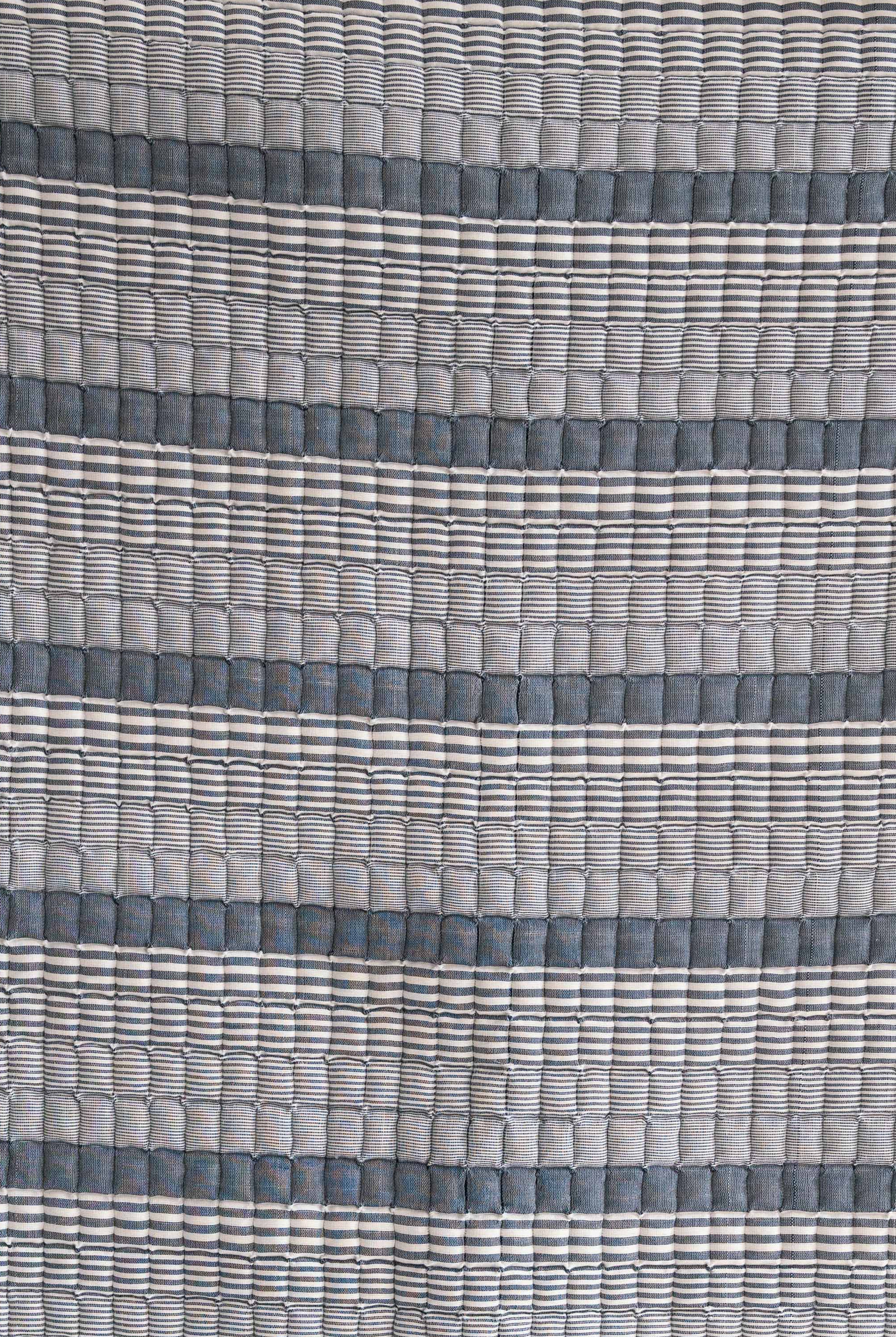 Close-up of blue striped Sujani quilt fabric with textured pattern