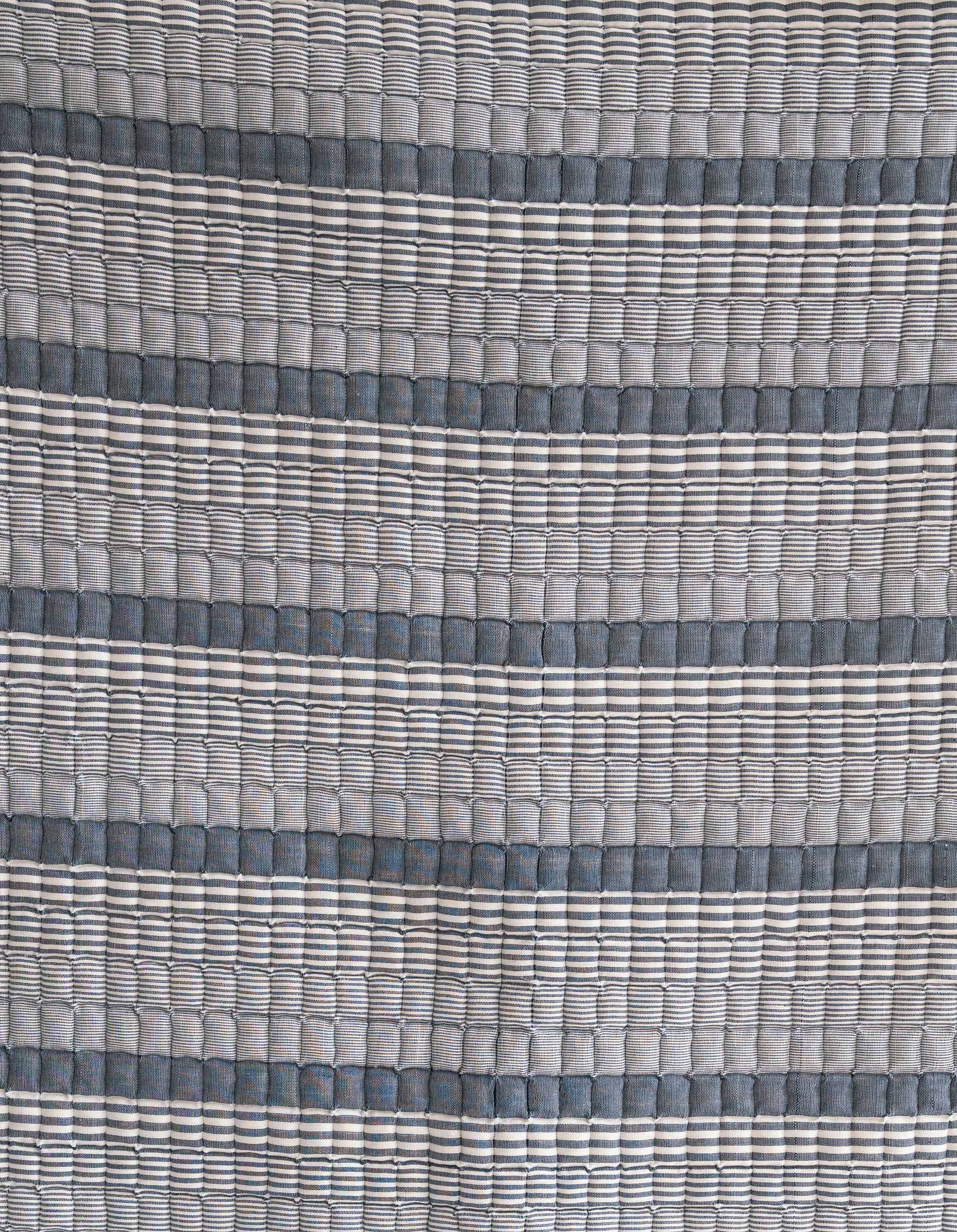 Close-up of blue striped Sujani quilt fabric with textured pattern