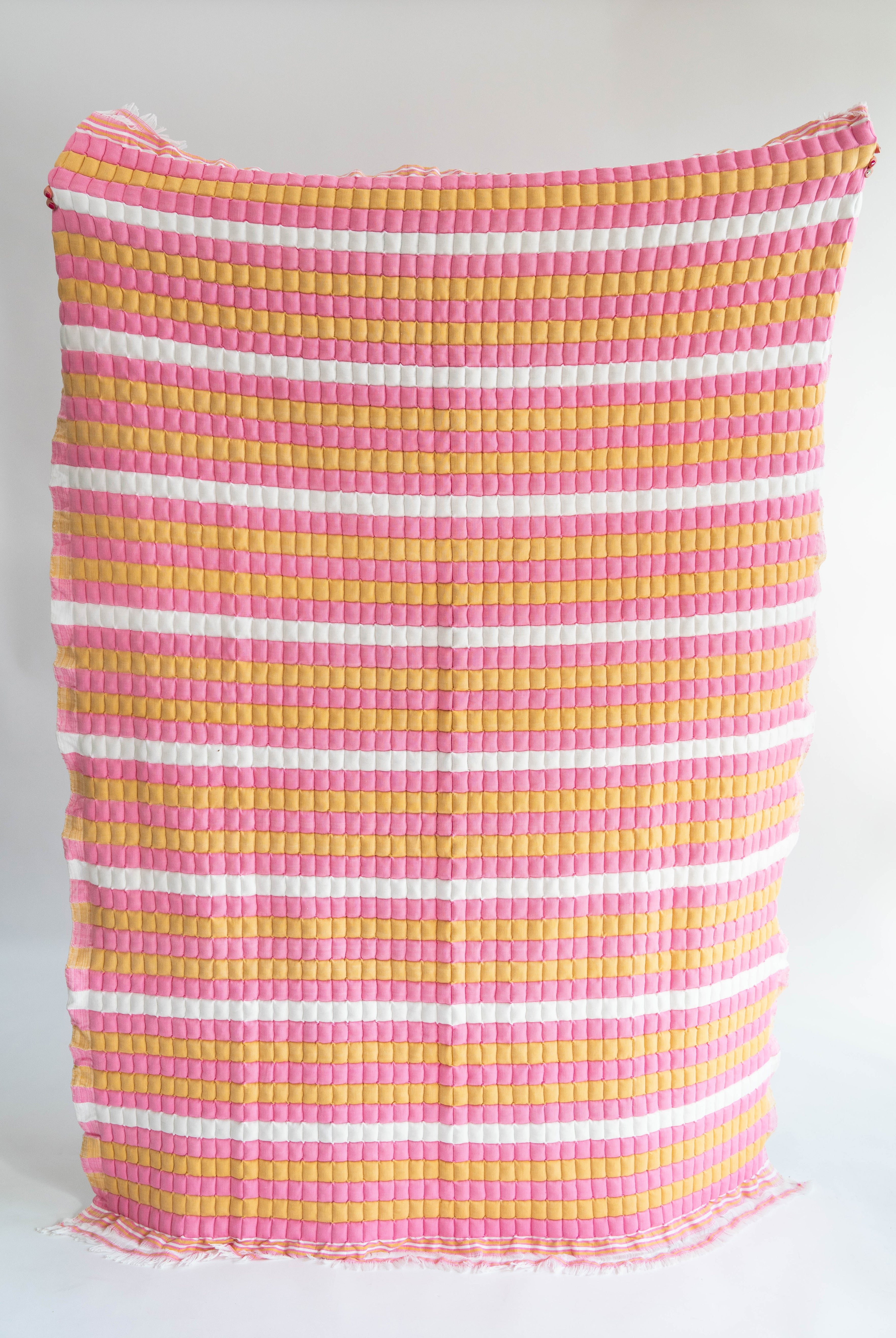 Pink, yellow striped sujani quilt with fringed edges, New York design studio