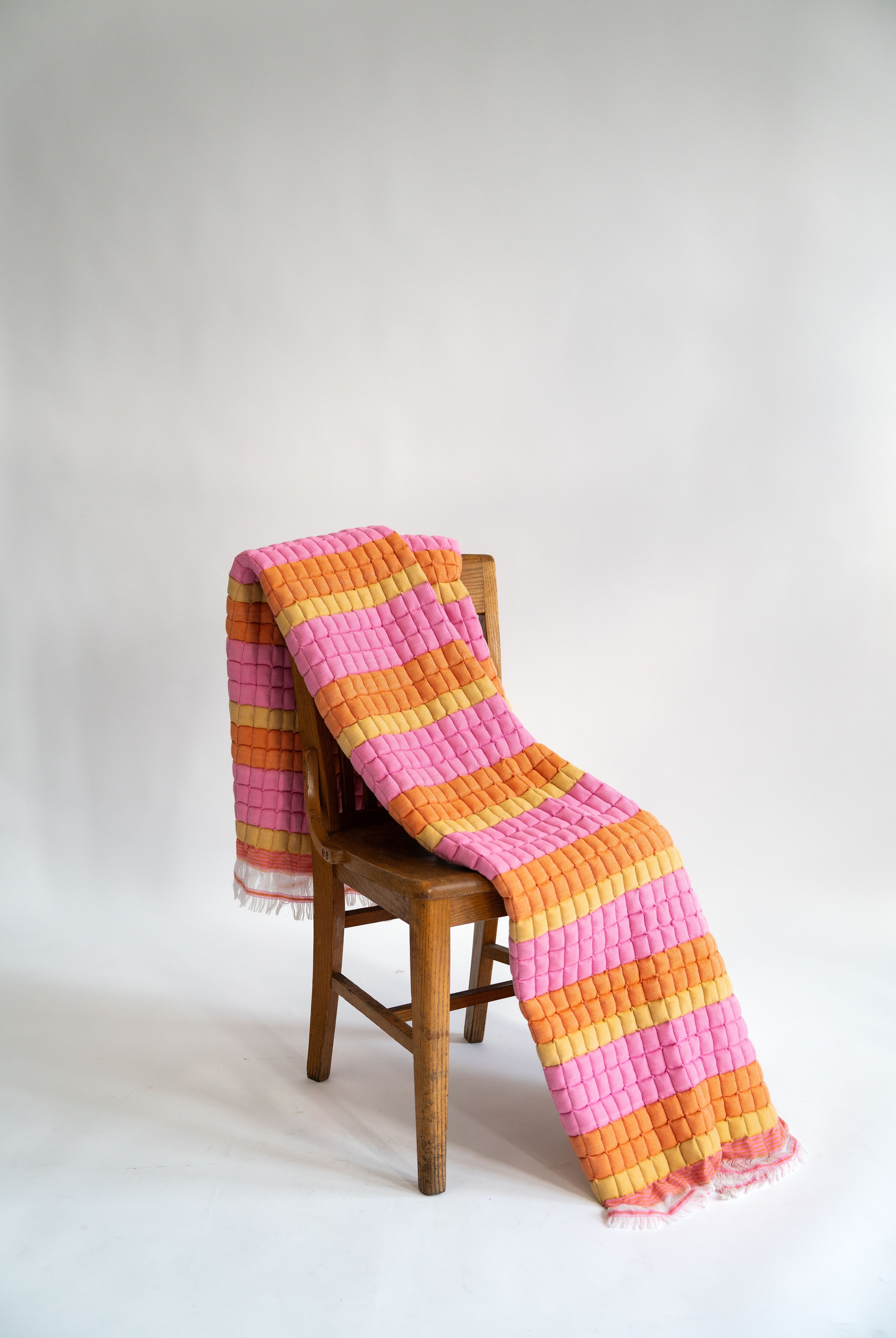 Inner Child Creamsicle Sujani quilt draped over wooden chair