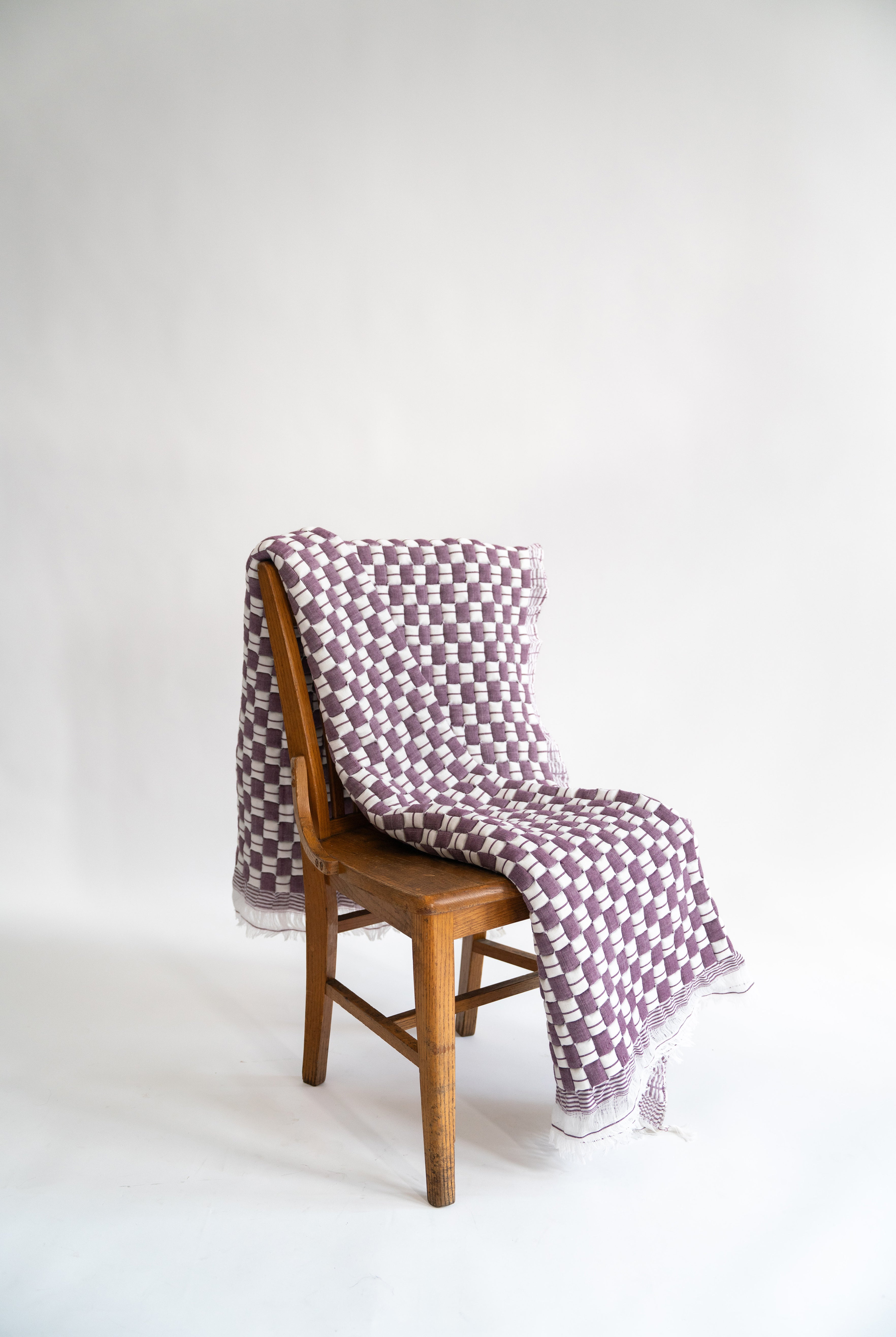 Purple checkered Sujani quilt draped over wooden chair - Inner Child