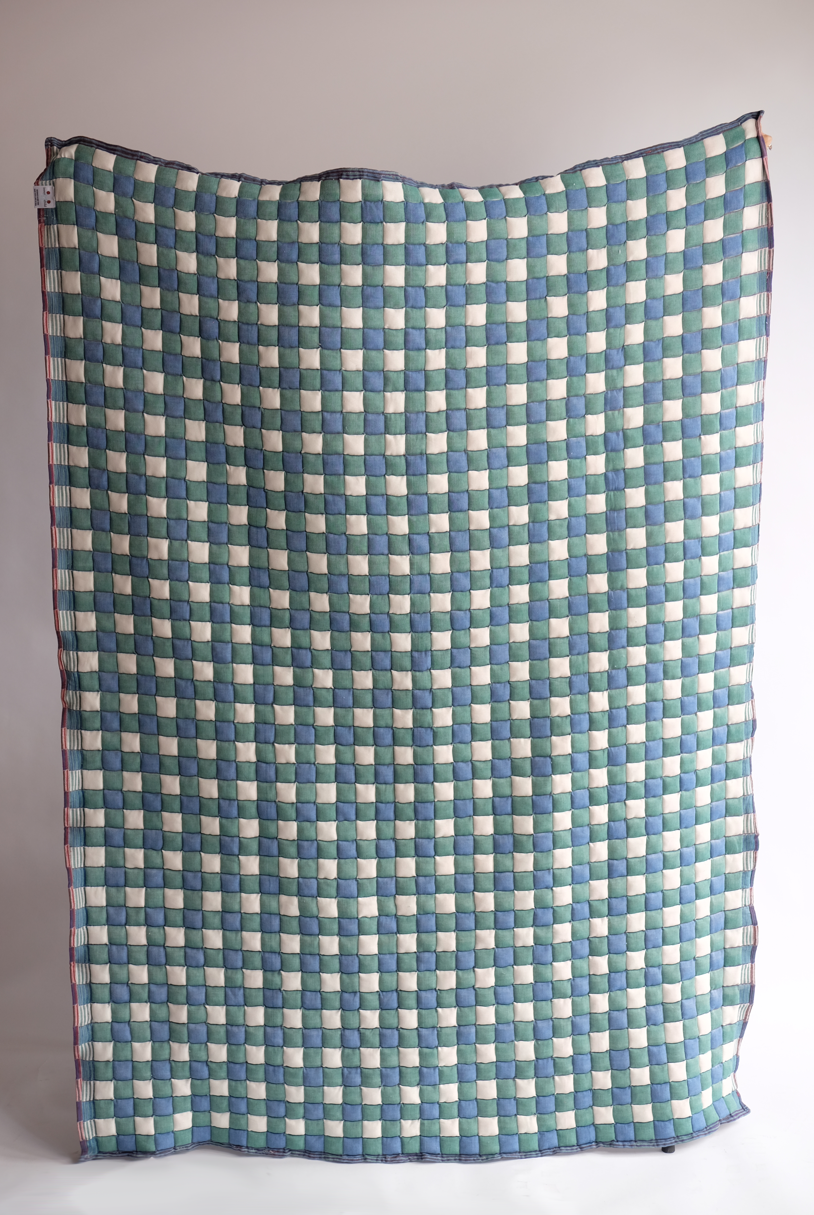 Green and blue checkered reversible Sujani quilt displayed flat