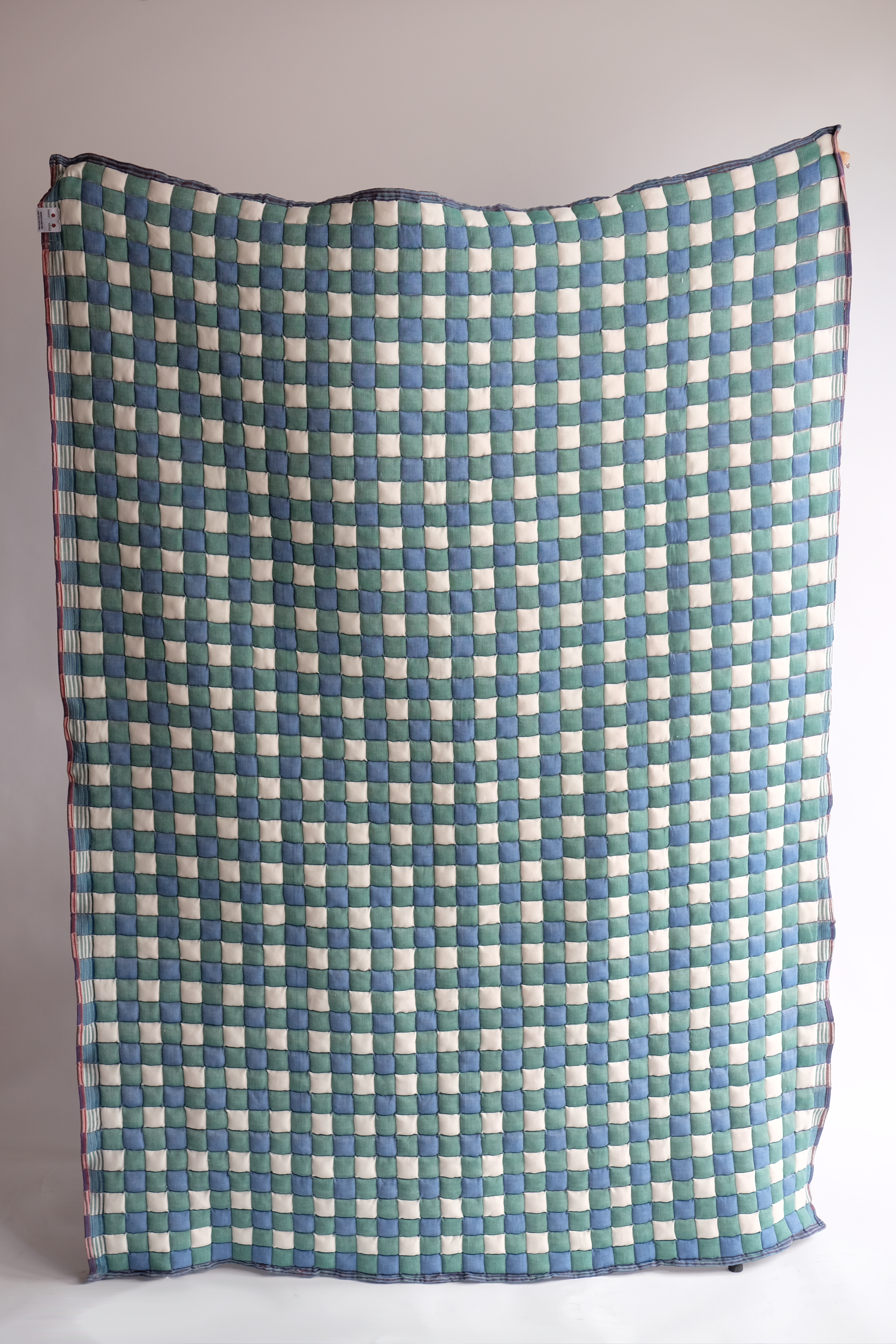 Green and blue checkered reversible Sujani quilt displayed flat