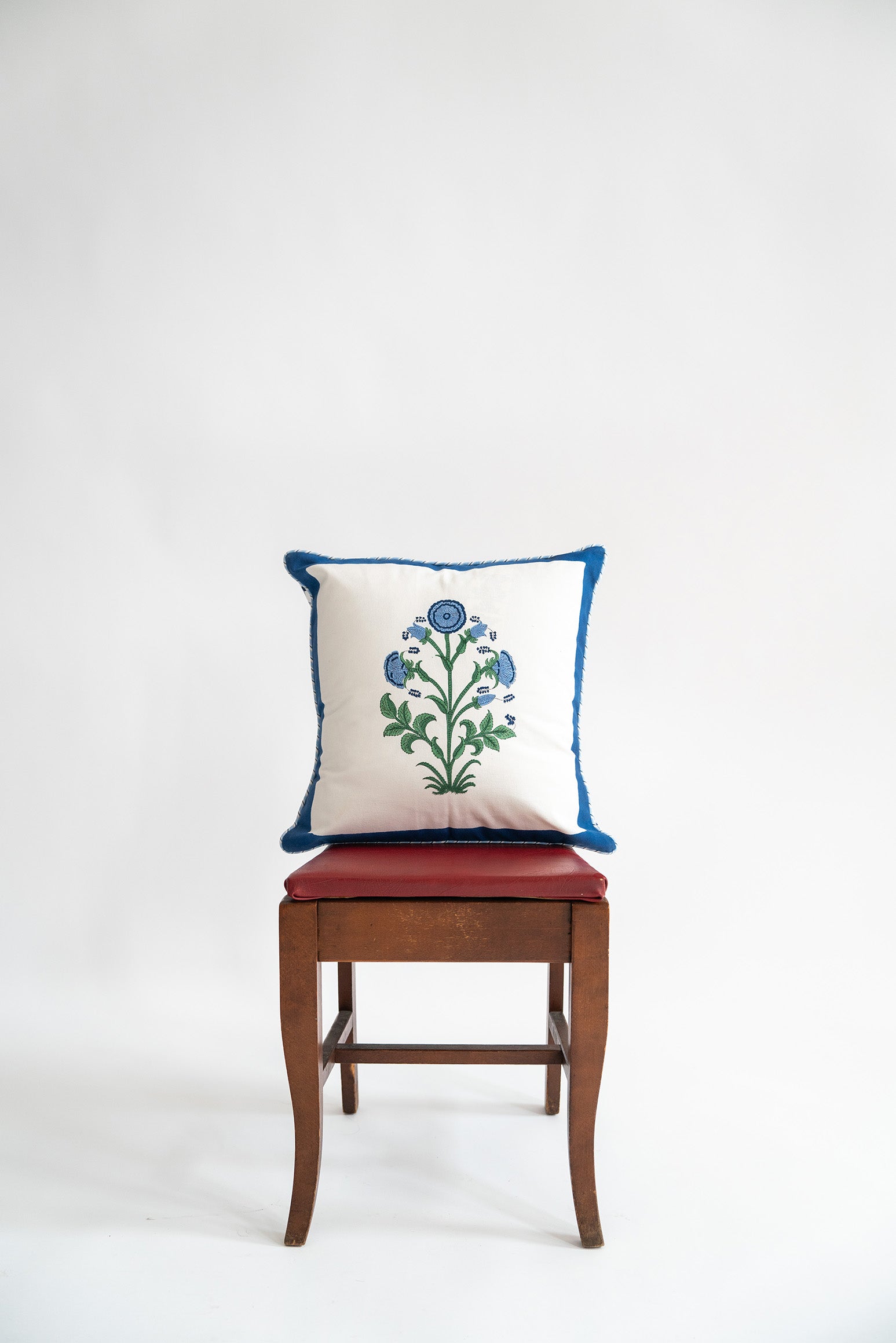 Cobalt-trimmed botanical blockprint pillow on wooden chair