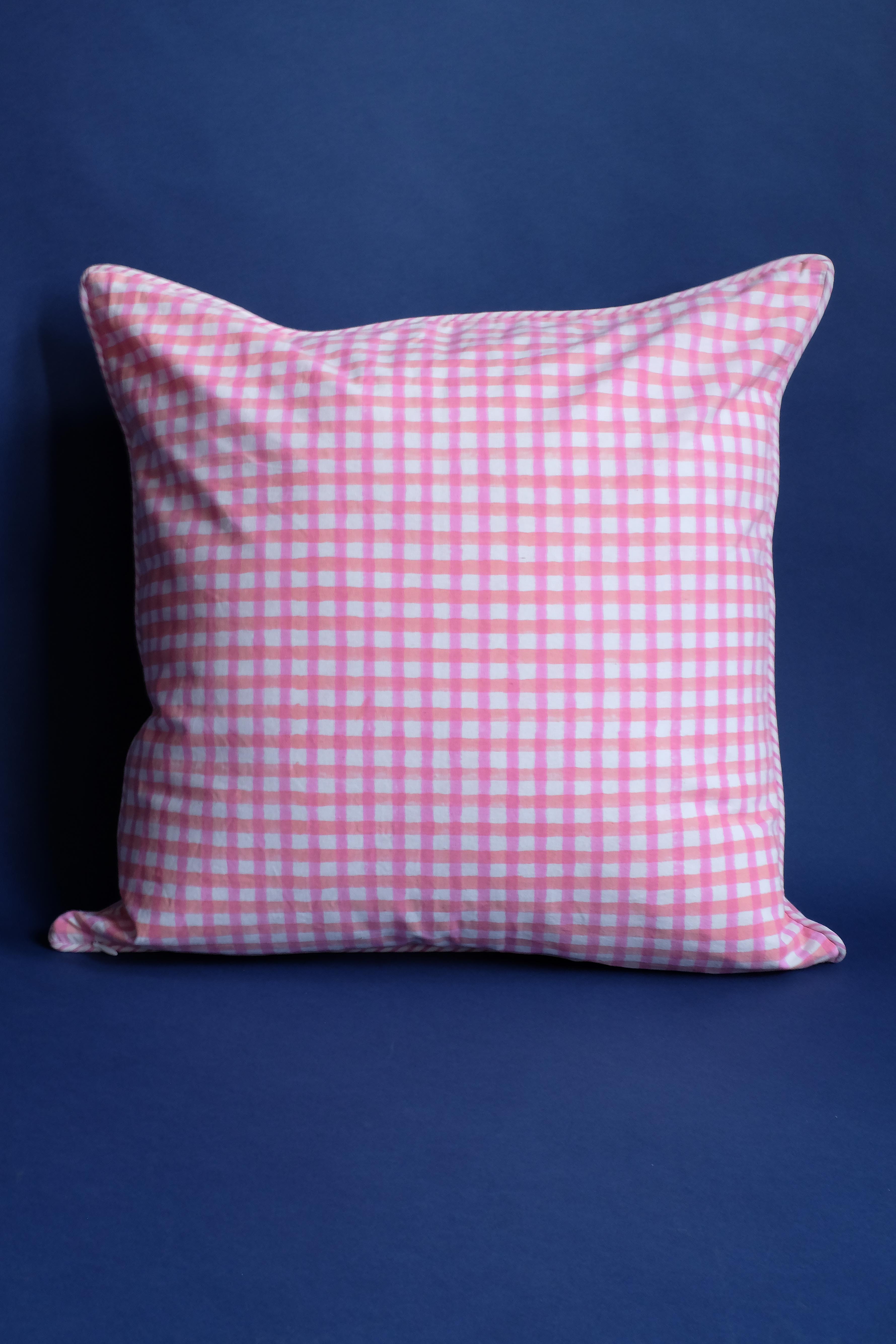 Pink gingham pillow on dark blue backdrop
