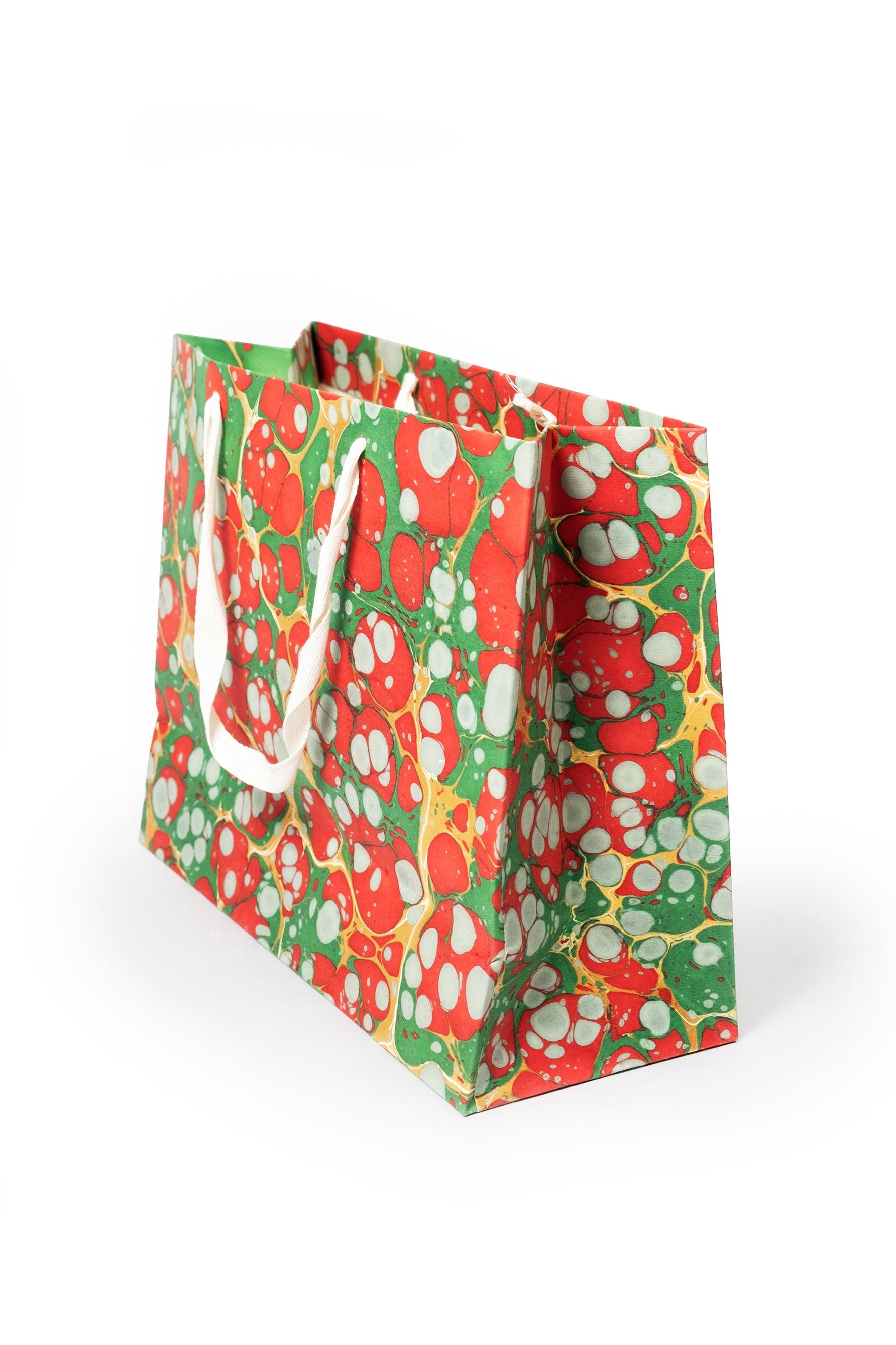 Christmas Gems hand-marbled gift bag in red, green, white, and gold with white handles, side view.