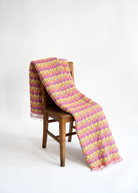 Vibrant cotton candy colored sujani quilt draped over wooden chair