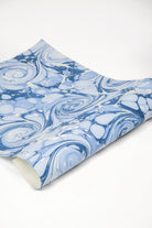 Close-up of hand-marbled blue ocean wave gift wrapping paper with swirling patterns