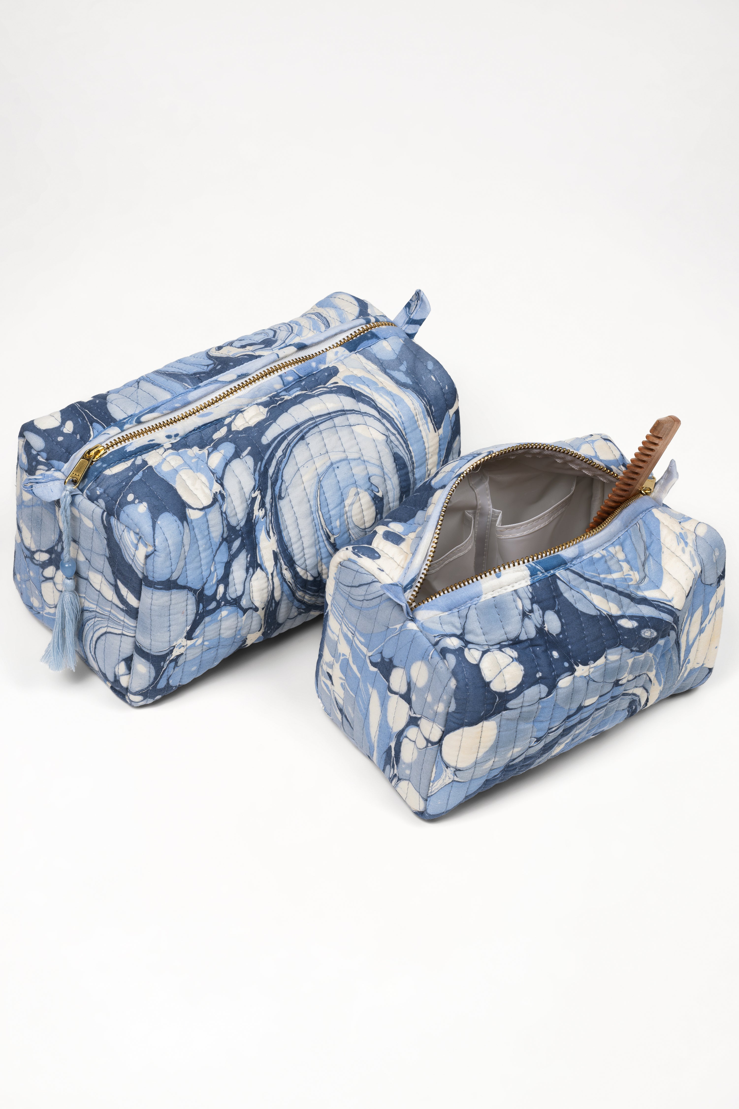 Two hand-marbled ocean wave cosmetic bags, one open to show interior zipper zipper