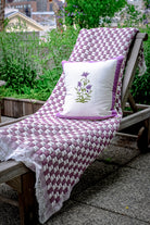 Lounge chair with purple woven blanket and pillow garden setting