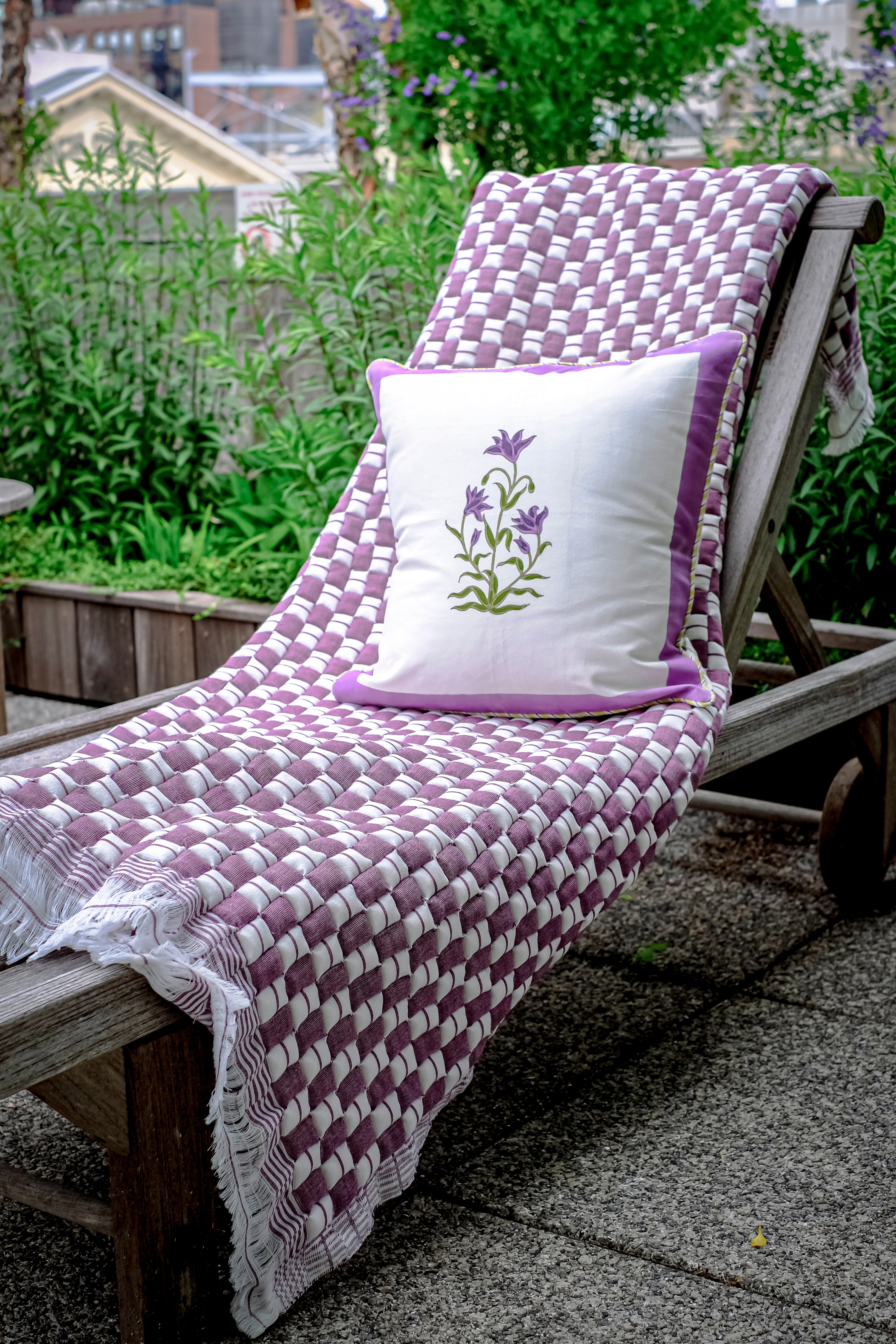 Lounge chair with purple woven blanket and pillow garden setting