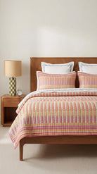 Bedroom with wooden bed, striped bedding, and a lamp on a nightstand.