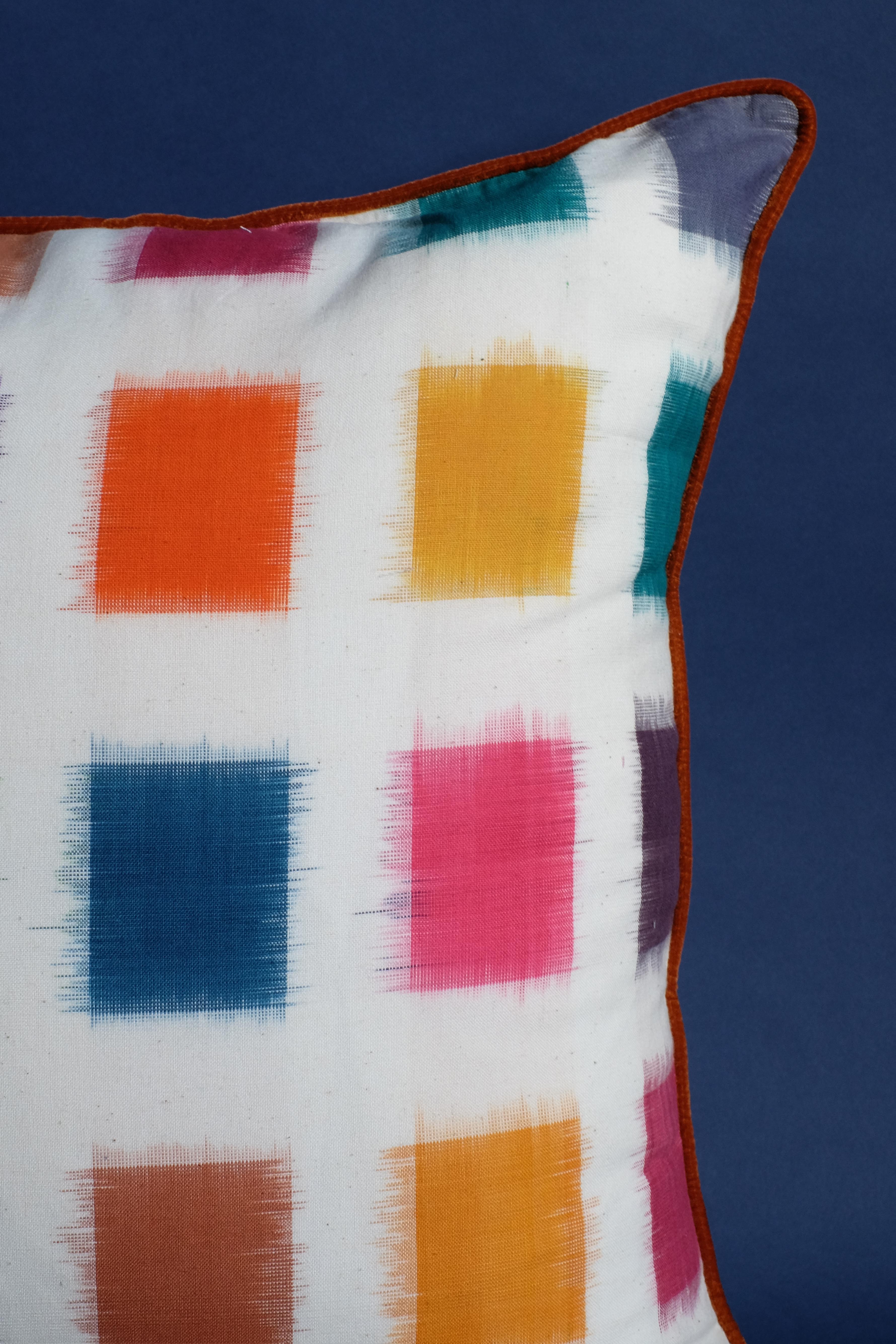 Close-up technicolor ikat pillow fabric with brown trim - dark blue background
